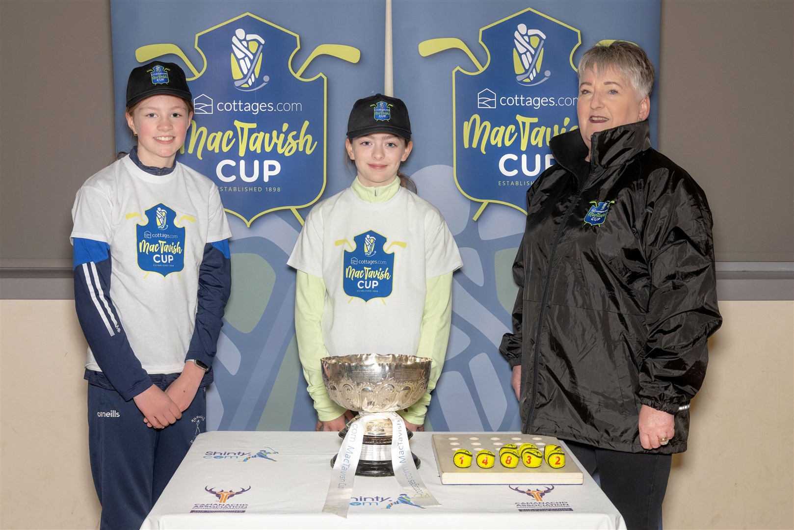 Maisie Ewing and Taylor Cameron, two attendees at a Camanachd Association girls camp at Kirkhill, along with Heather Grant, Business Development Manager for cottages.com made the draw.