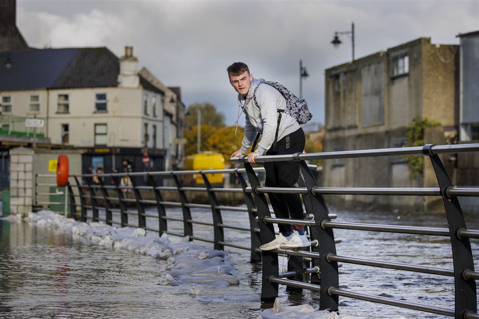 A man walks along a fence to avoid floodwater in Newry, Co Down on Tuesday (Liam McBurney/PA)