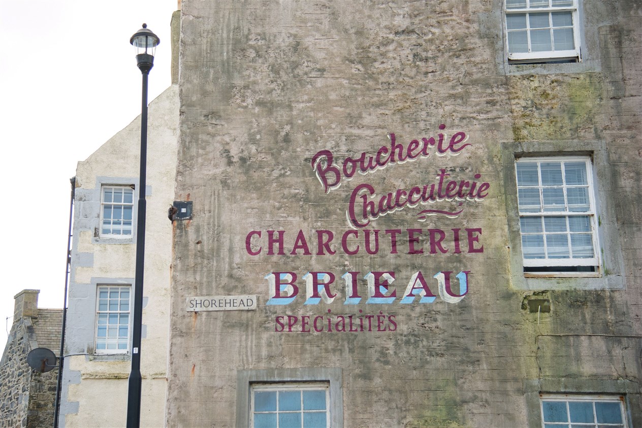 'Boucherie Charcuterie Charcuterie Brieau Specialites' was painted on the side of this harbour facing building. The area around the harbour in Portsoy underwent a transformation ahead of the filming of Peaky Blinders. Picture: Daniel Forsyth