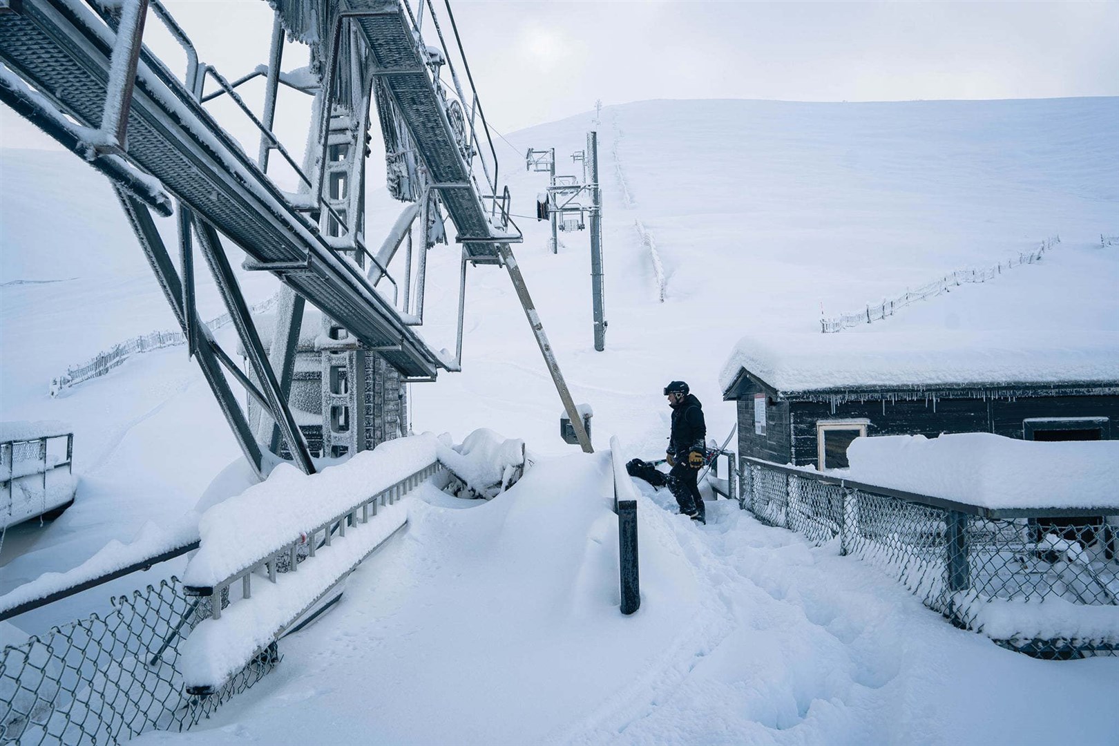 A Cairngorm Mountain worker digs out part of the West Wall Poma lift with fantastic snow conditions on the run and in the Aonach Bowl in the background.