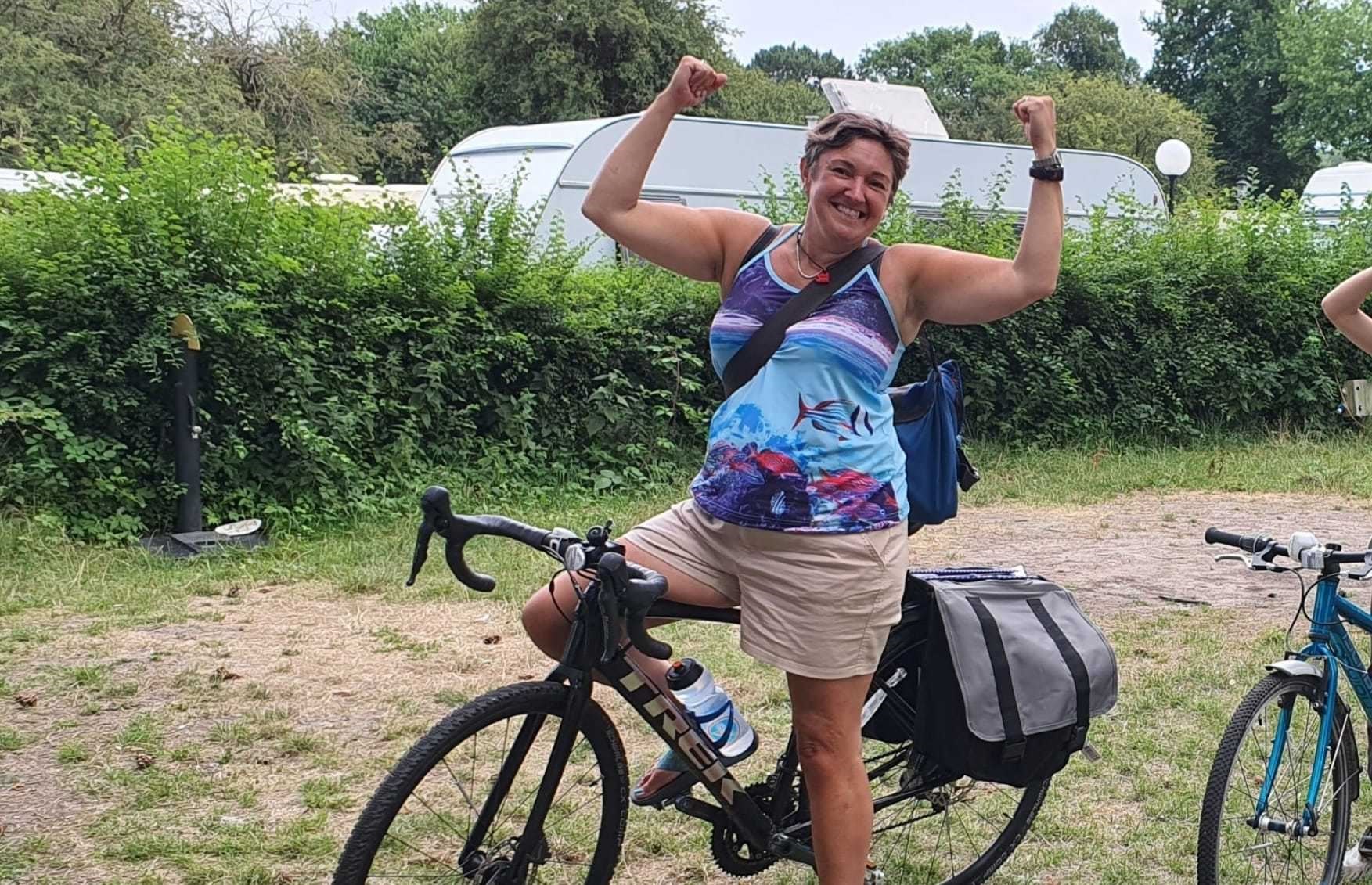 ALT TEXT: Sara Ramsey is sitting astride a black Trek touring bike. She is wearing shorts and a T-shirt. She has her arms up in ‘strong man’ pose and she’s smiling at the camera. Sara Ramsey from Inverness, Highland, has been selected as one of Cycling UK's 100 Women in Cycling announced on 23 November. Every year the 100 Women in Cycling list celebrates inspirational women who are encouraging others to experience the joy of cycling. Sara Ramsey has been nominated as a community champion for her work in setting up and continuing to run Kidical Mass North, Inverness, Scotland’s first Kidical Mass group.