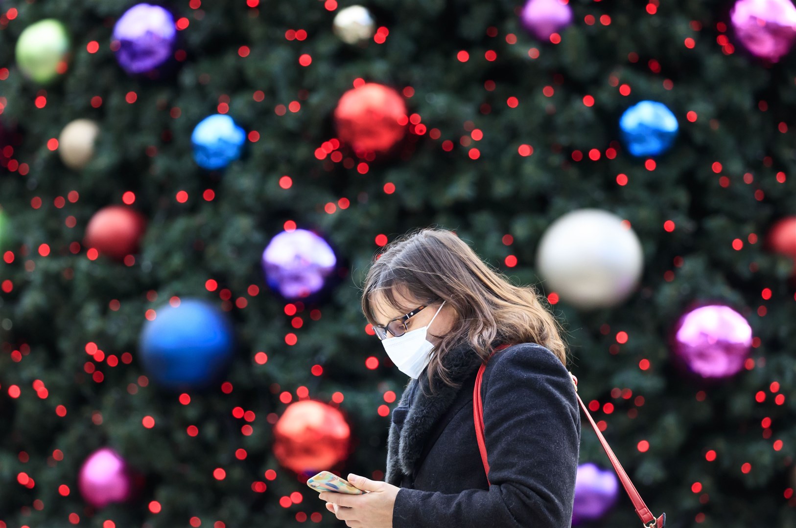 A woman walks past a Christmas tree in Leeds (Danny Lawson/PA)
