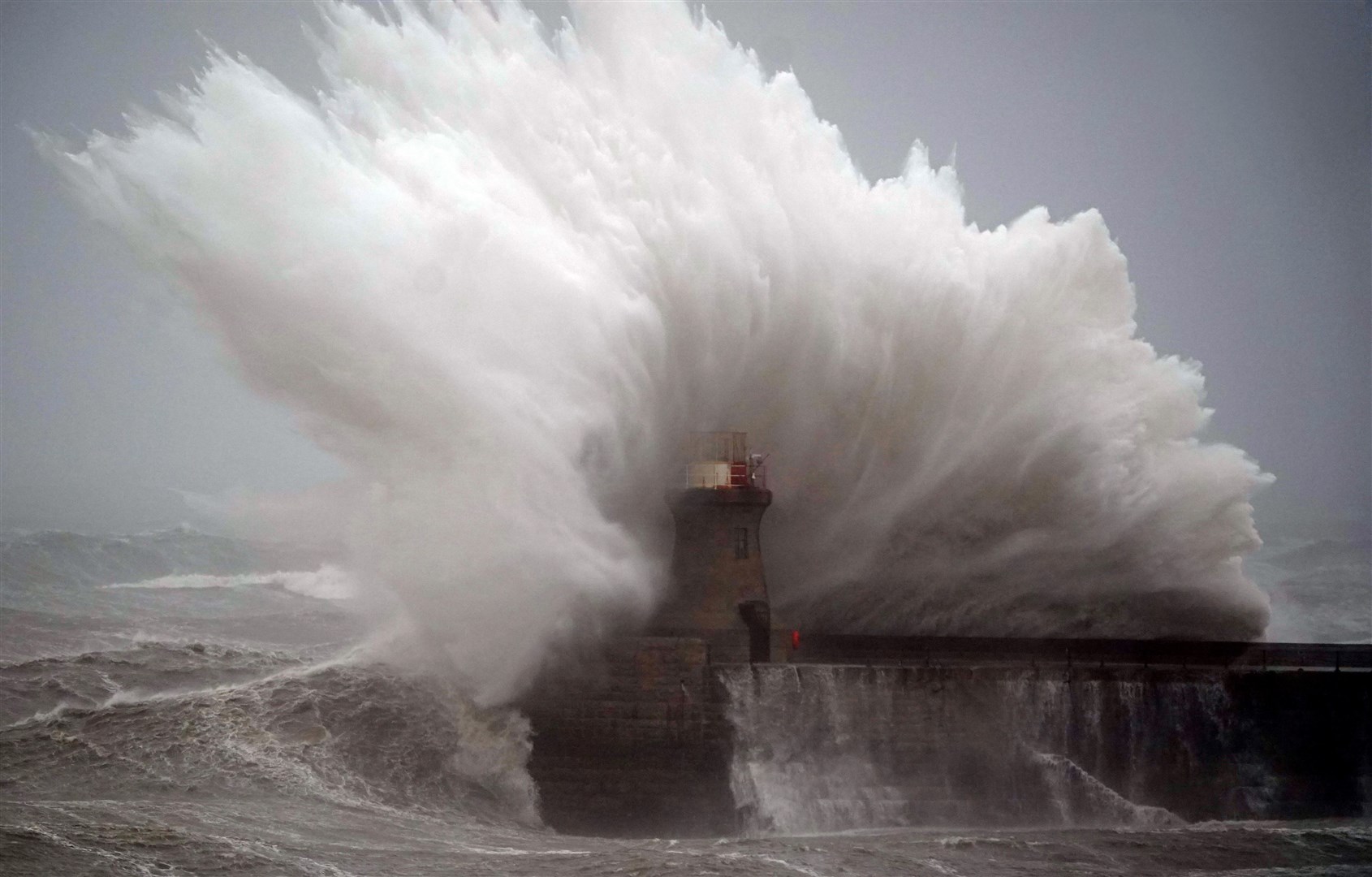 Waves crash against South Shields lighthouse after the top was ripped off by Storm Babet (Owen Humphreys/PA)