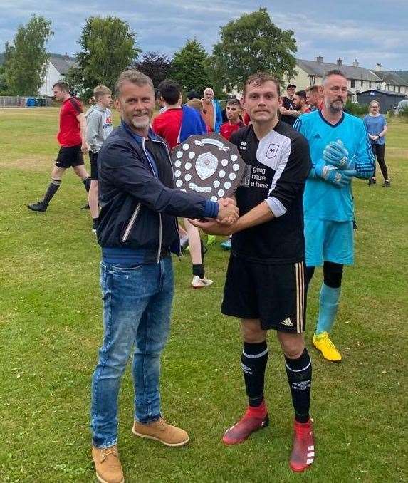 Brian Ritchie presents the trophy to Boat of Garten's player-manager Connor Macleod.