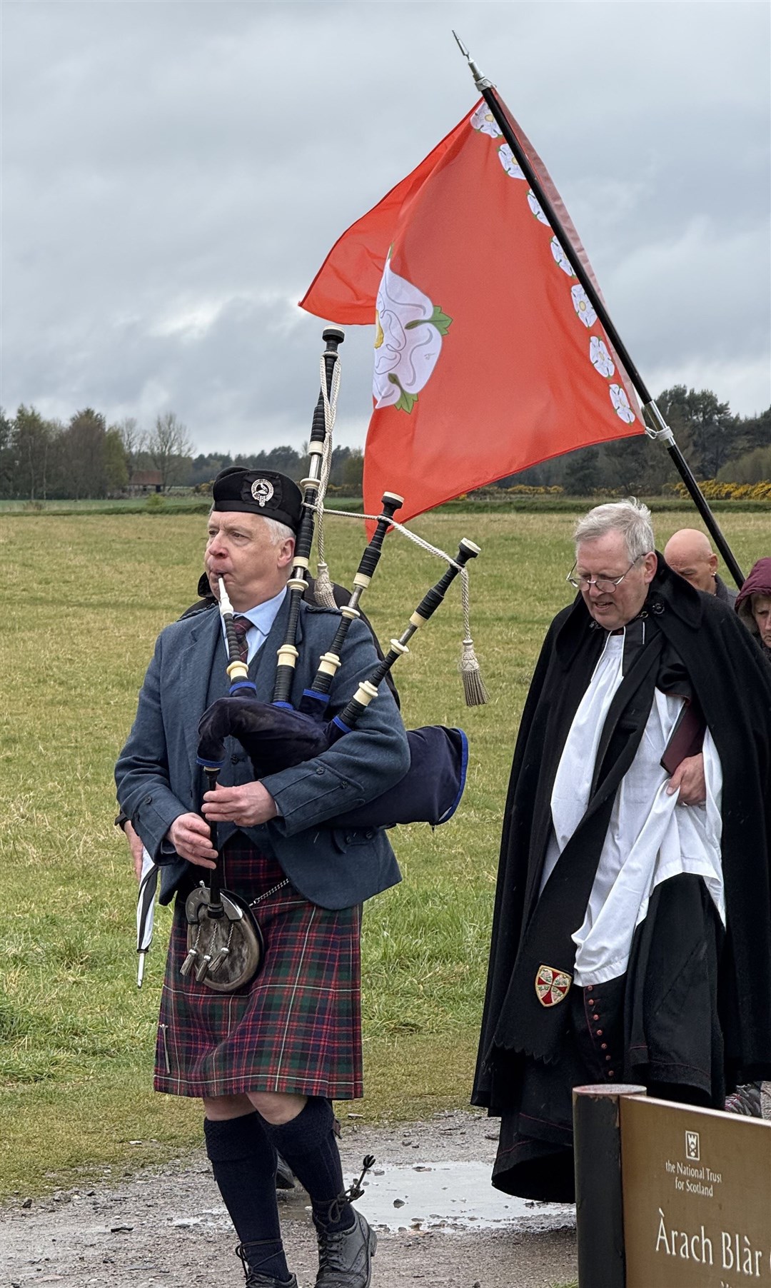 A piper leading the way to the memorial cairn to start the service.
