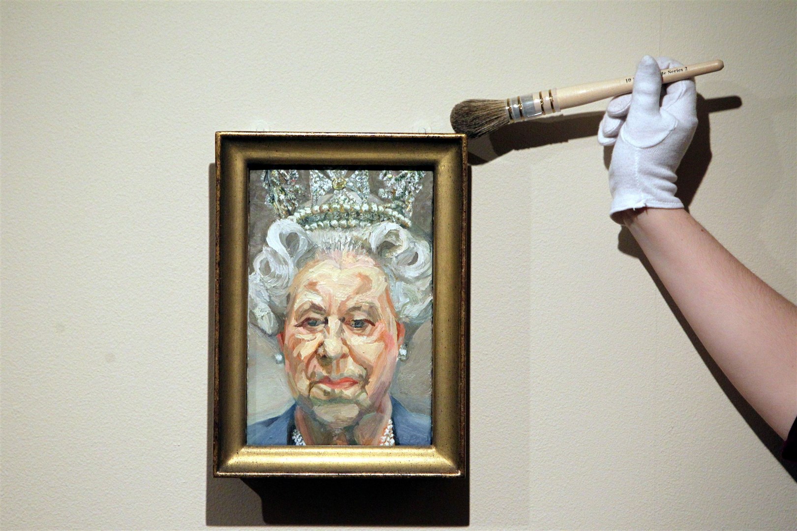Curator Lauren Porter dusts a portrait of the Queen by Lucian Freud, who declined an award (Steve Parsons/PA)