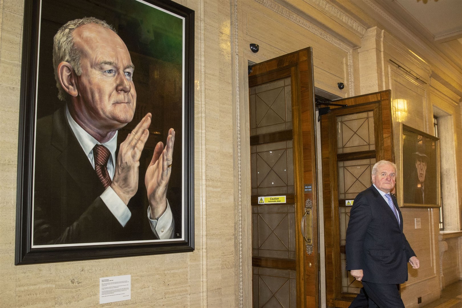Bertie Ahern passes between portraits of former deputy first minister Martin McGuiness (left) and former first minister Ian Paisley (Liam McBurney/PA)