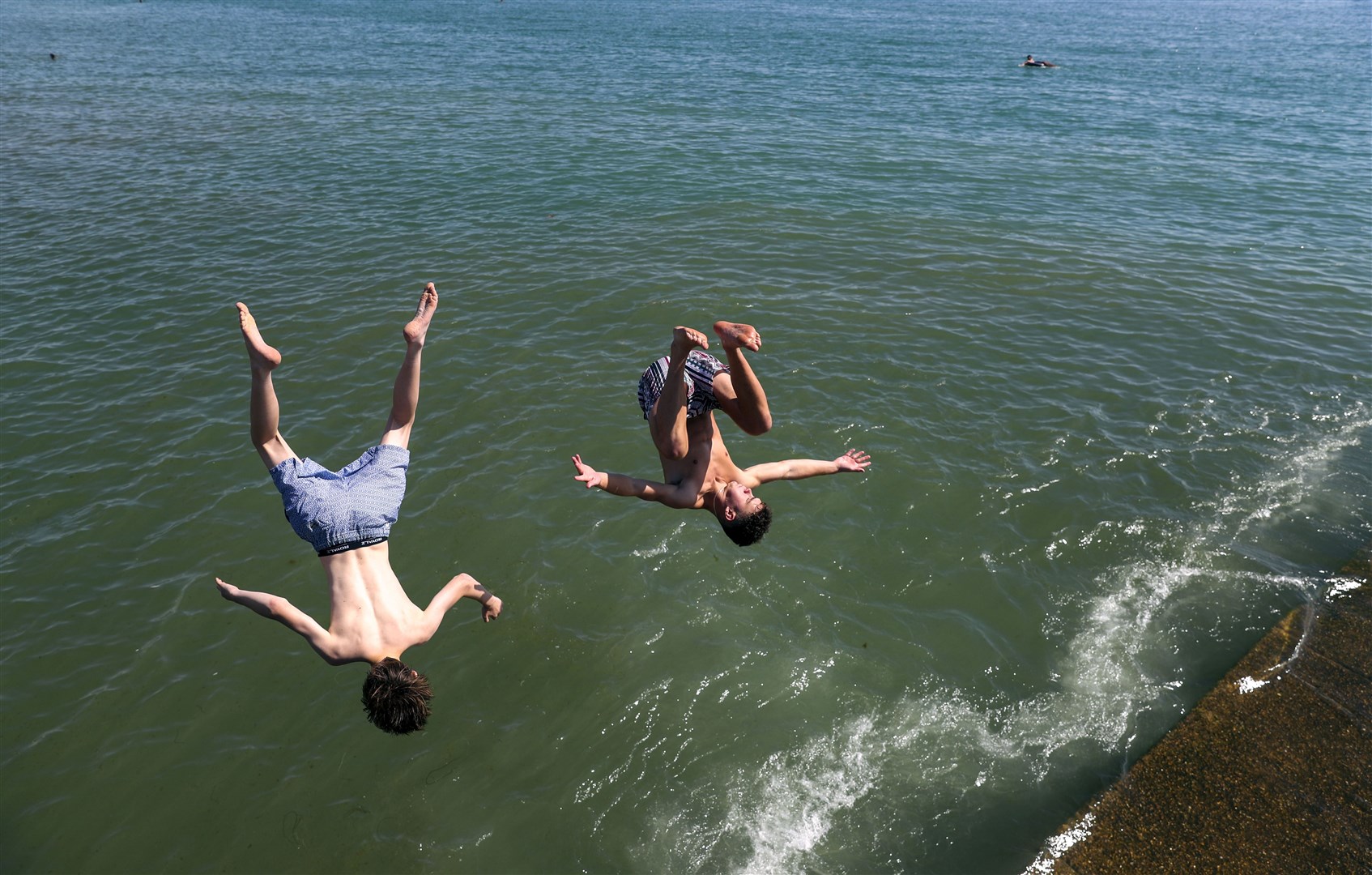 Felix and Josh jump into the sea at Brighton. Thousands flocked to the coast as temperatures soared in August (Steve Parsons/PA)
