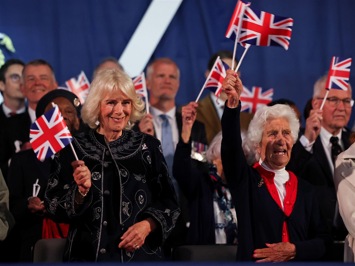 The Queen and Mavis Bensley wave flags during the concert (Chris Jackson/PA)