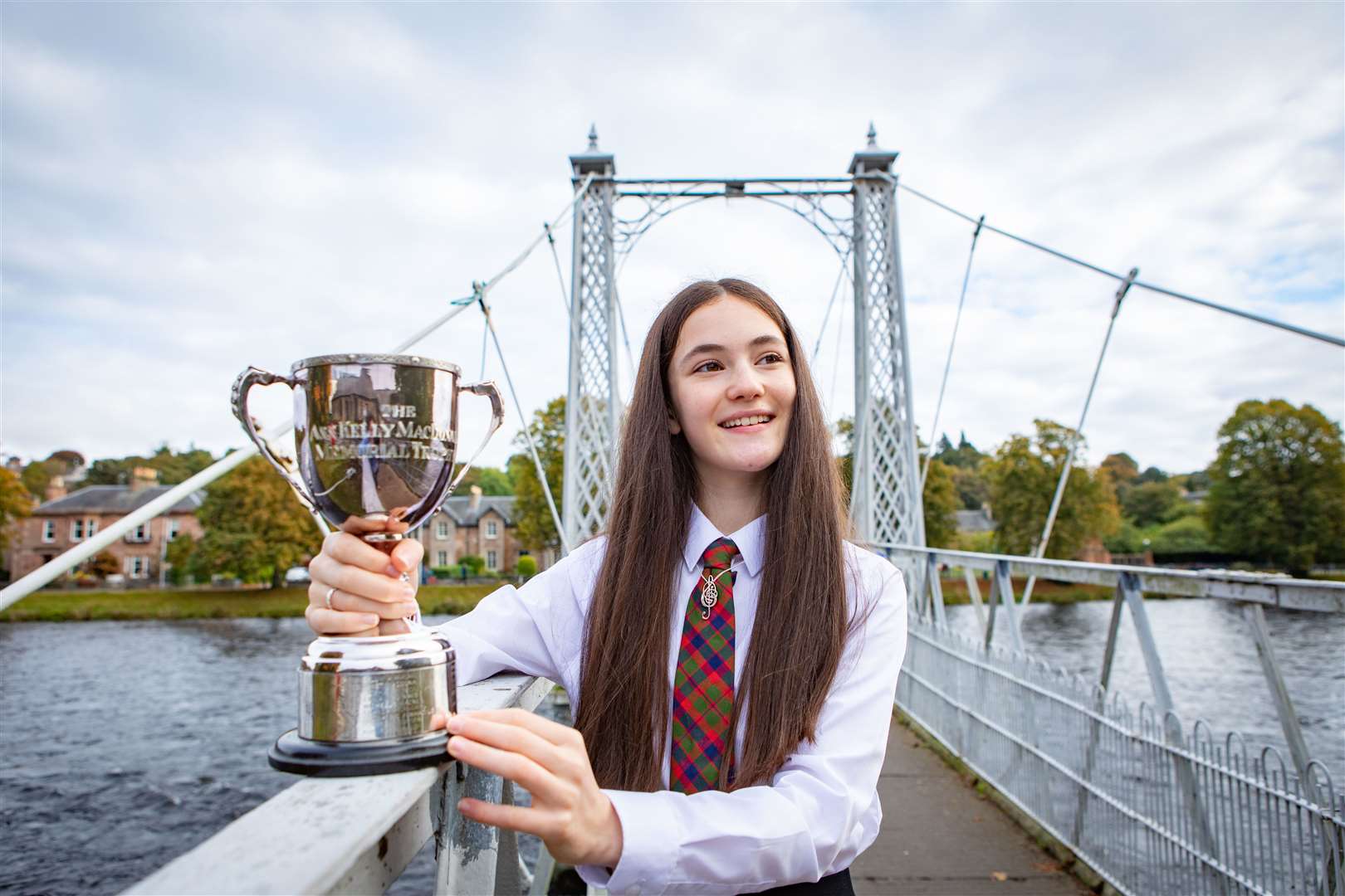 Picture shows Maria Monk, age, from Glasgow Gaelic School winner of the Solo Singing Fluent - Girls ages 13-15 - Traditional Silver Pendant at The Royal National Mòd 2021, in Inverness, Scotland, photographed wearing her Silver Pendant prize and holding the Ann Kelly MacDonald Memorial Trophy at the River Ness on Tuesday 12th October 2021