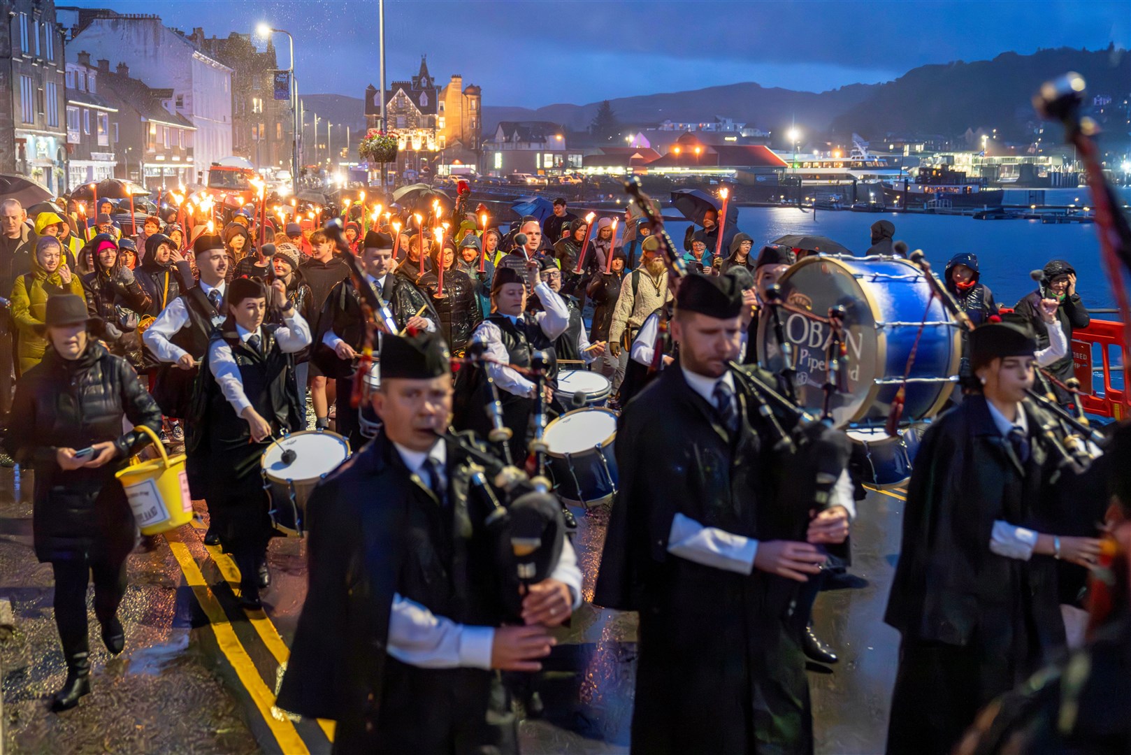 A packed torchlit procession took place through the streets of Oban, led by Oban Pipe Band, Deputy First Minister Kate Forbes, members of An Comunn Gàidhealach and the local organising committee, getting The Royal National Mòd formally underway on Friday evening. Undeterred by the west coast weather, the Oban community came out in force to witness the spectacle and follow the procession from Station Square, along the esplanade to the event’s flagship event, The Corran Halls.