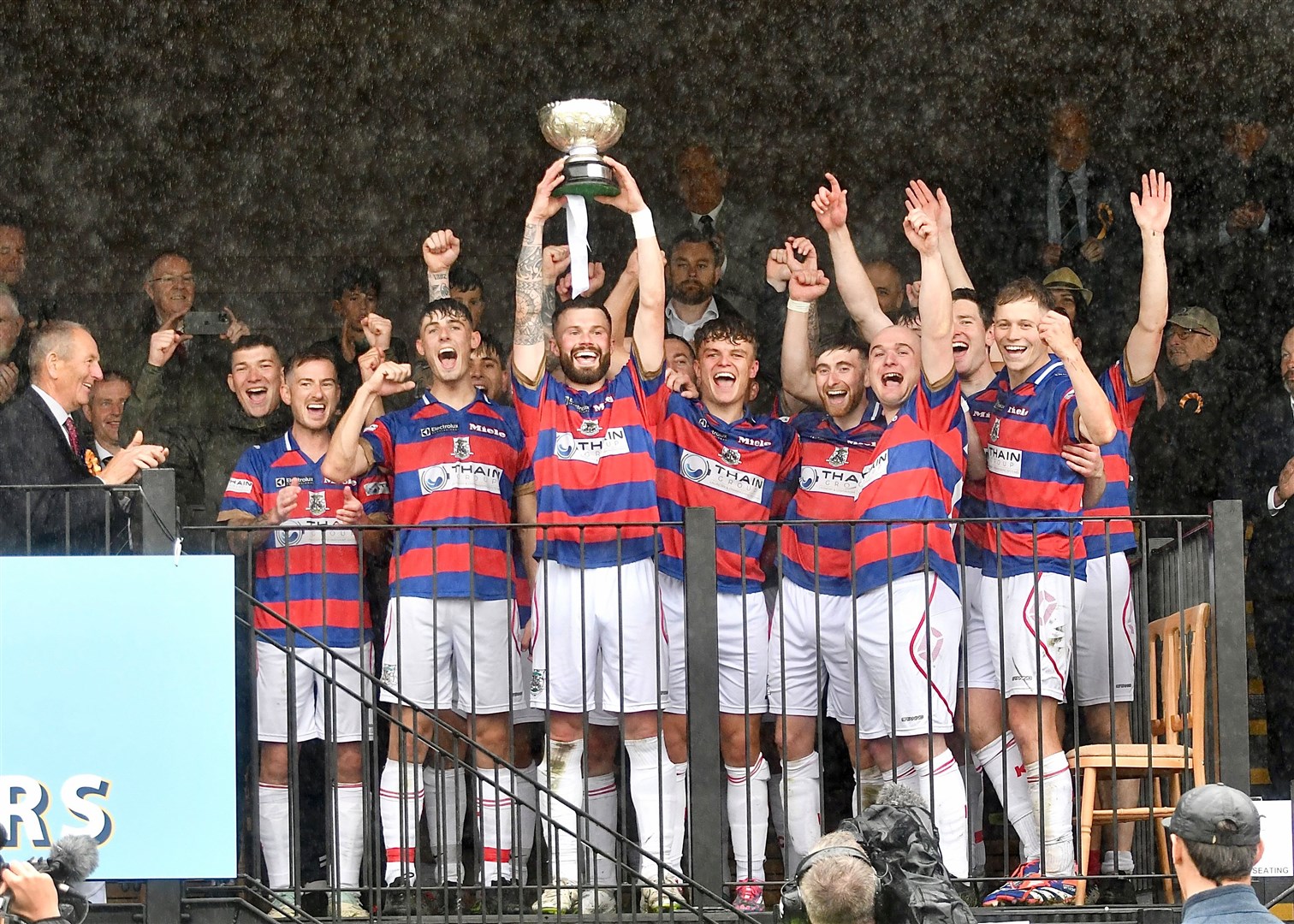 Skipper Thomas Borthwick lifts the cup in front of his ecstatic teammates.