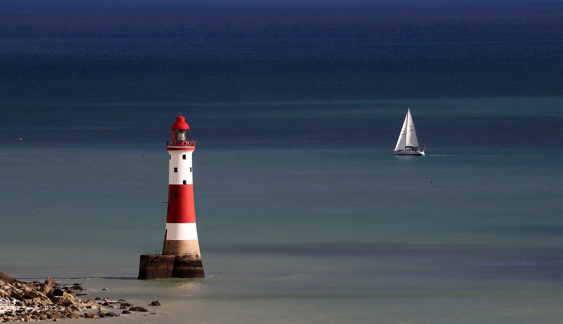 A yacht sails past Beachy Head lighthouse near Eastbourne in Sussex (Gareth Fuller/PA)