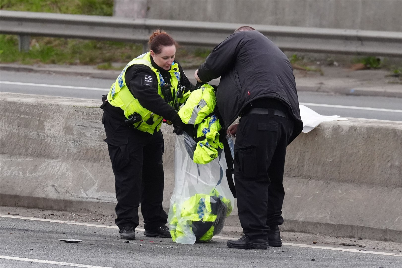 Emergency services personnel retrieve police clothing from the scene (Owen Humphreys/PA)