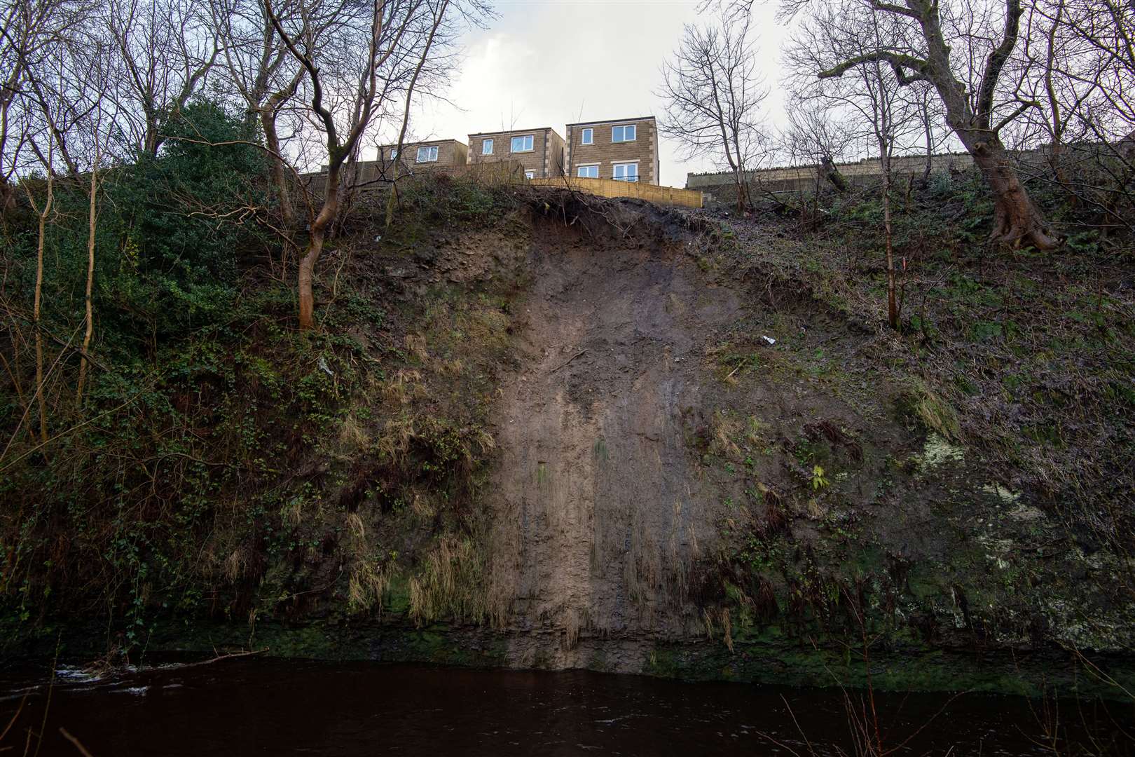 The back gardens of residential properties on Manchester Road, Slaithwaite, sit precariously near to the edge of a landslide on the banks of the River Colne near Huddersfield, West Yorkshire (Joe Giddens/PA)