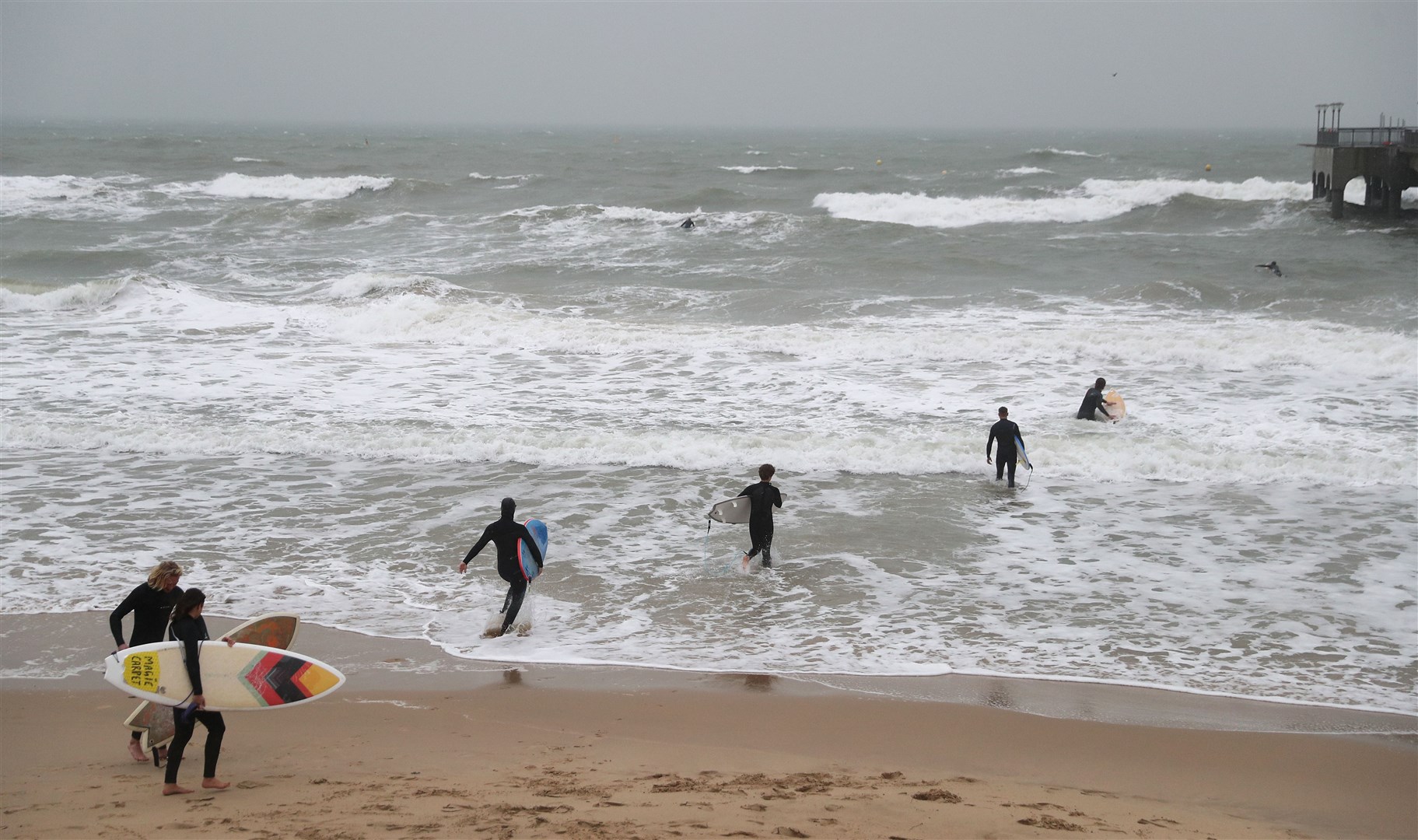 Surfers make their way into the sea at Boscombe beach in Dorset (Andrew Matthews/PA)