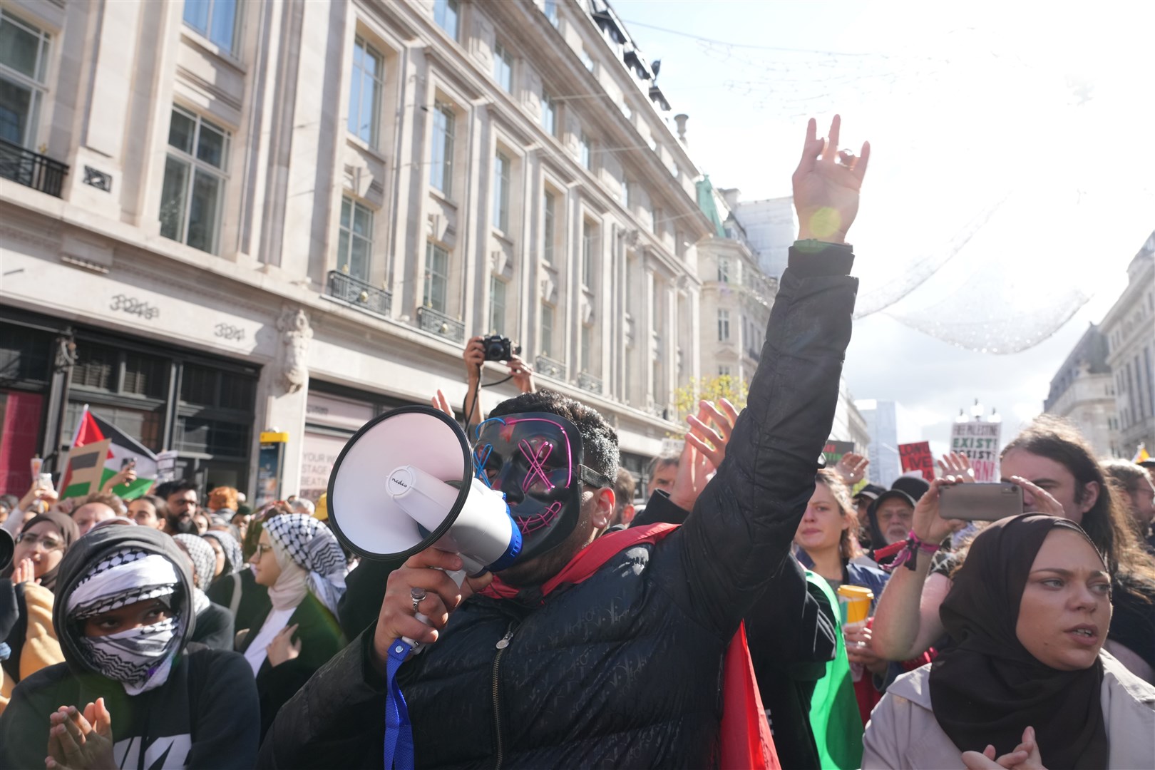A masked supporter shouts through a megaphone during the march (Jeff Moore/PA)