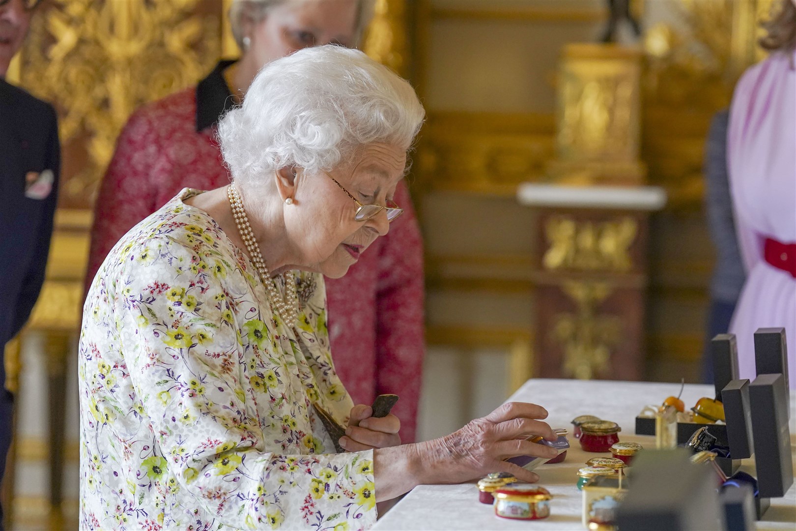The monarch views a display of artefacts from British craftwork company, Halcyon Days, to commemorate the company’s 70th anniversary in the White Drawing Room at Windsor Castle, Berkshire (Steve Parsons/PA)