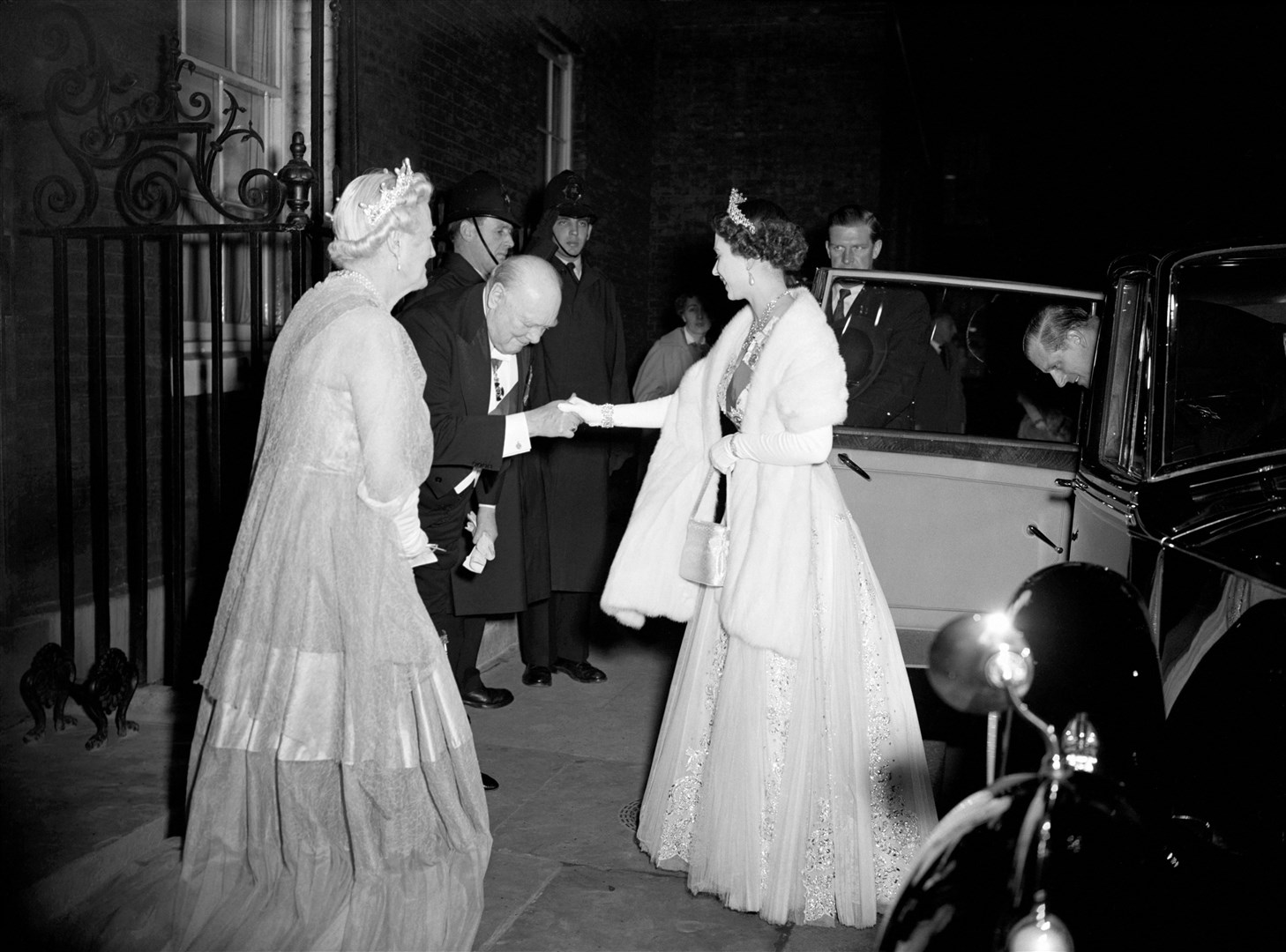 Sir Winston Churchill welcomes the Queen as she arrives for dinner at Downing Street in 1955 (PA)