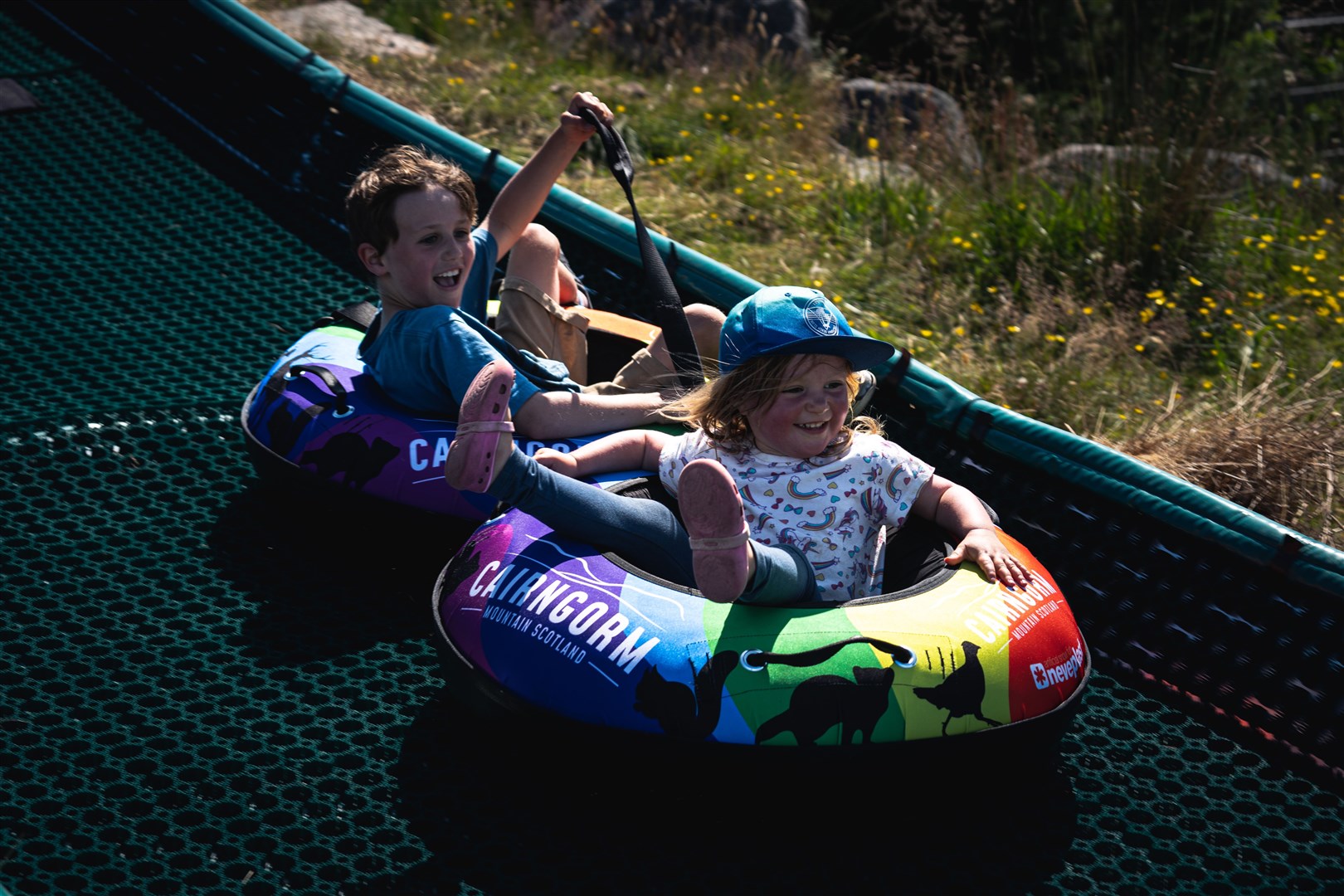 Two children enjoying a tube slide ride at Cairngorm Mountain.
