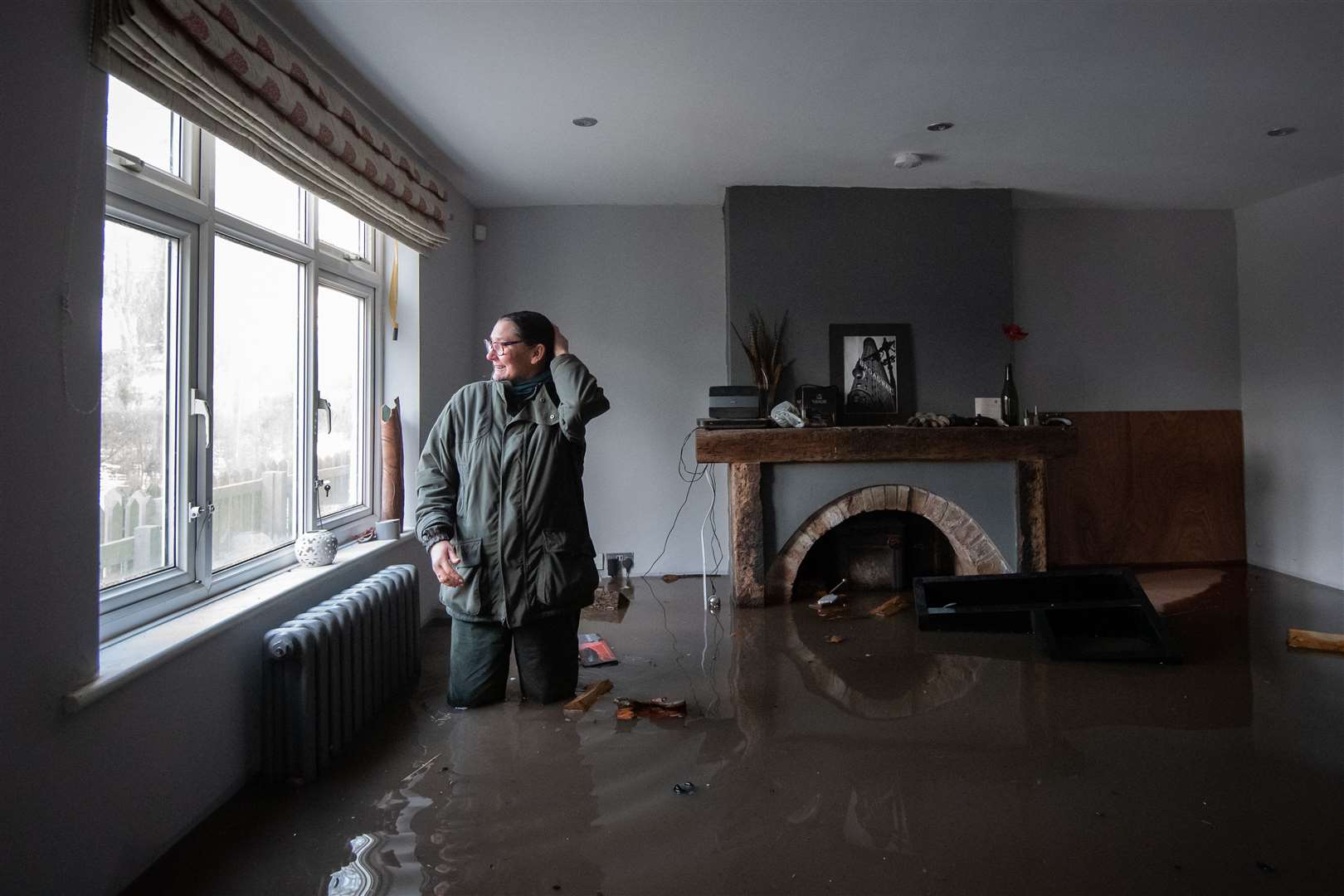 Gabrielle Burns-Smith looks out from her flooded home on the outskirts of Lymm in Cheshire (Joe Giddens/PA)