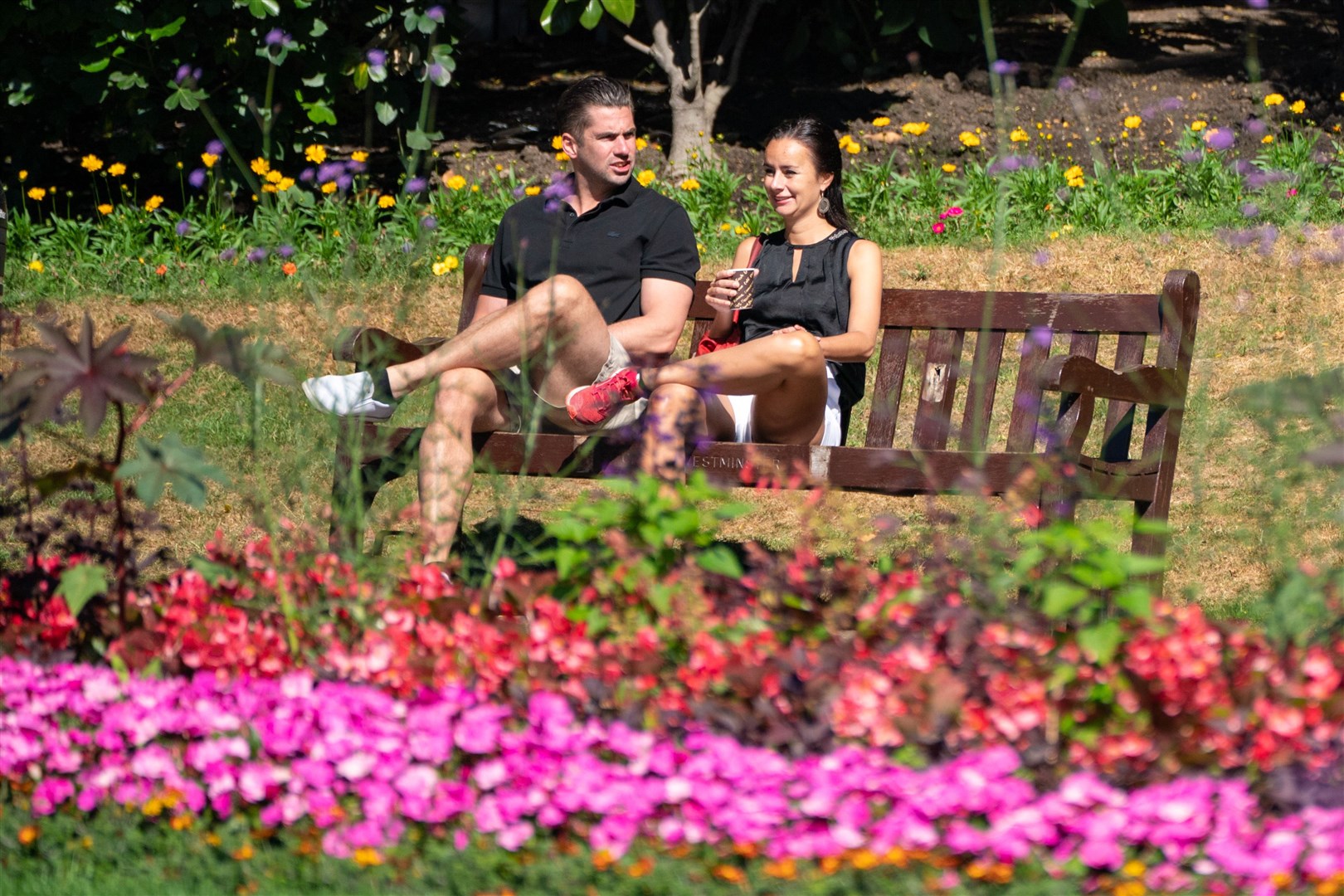 Two people enjoy the sun in Embankment Gardens, central London (Dominic Lipinski/PA)