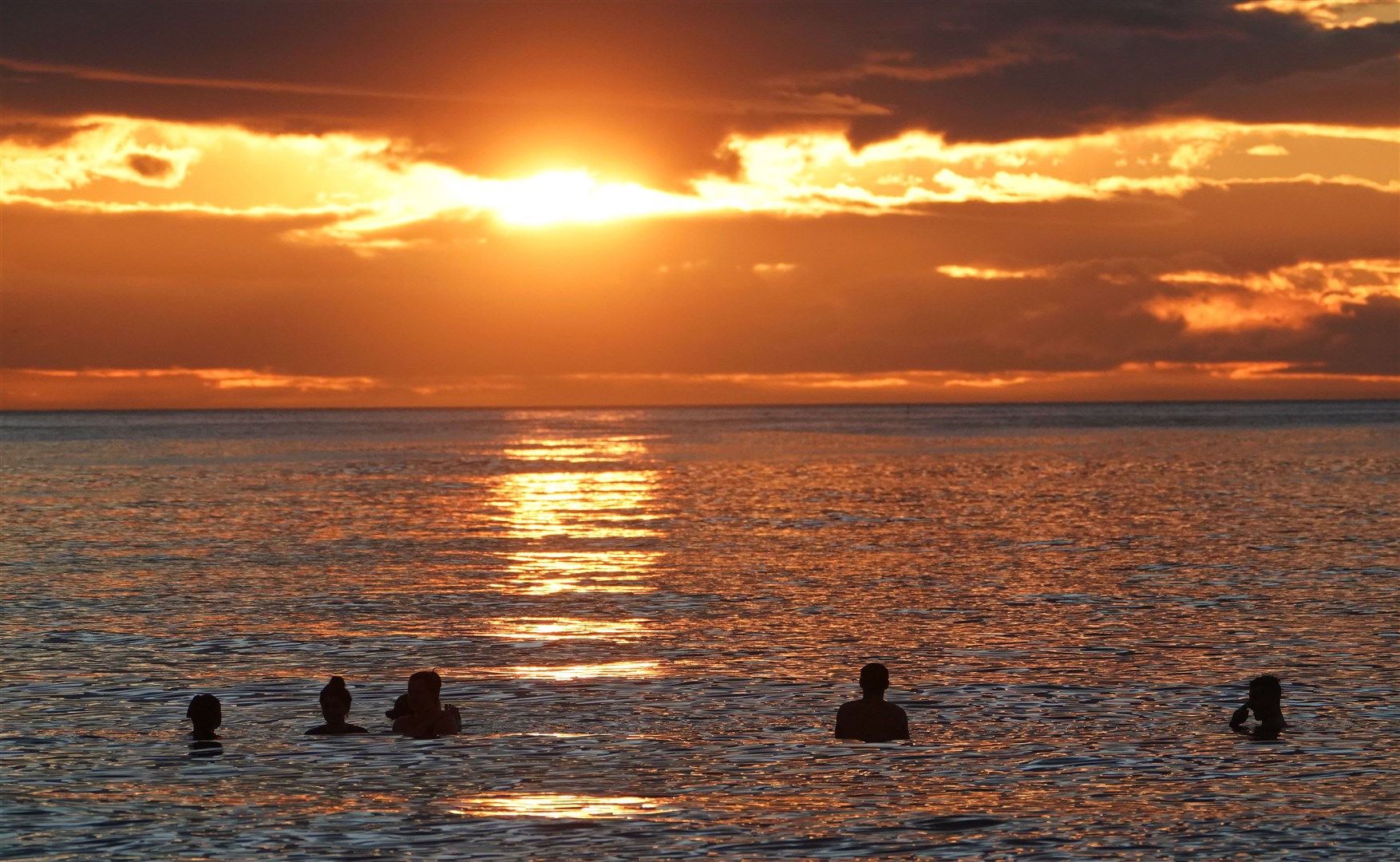 People in the sea at Tynemouth as the sun rises on the summer solstice (Owen Humphreys/PA)