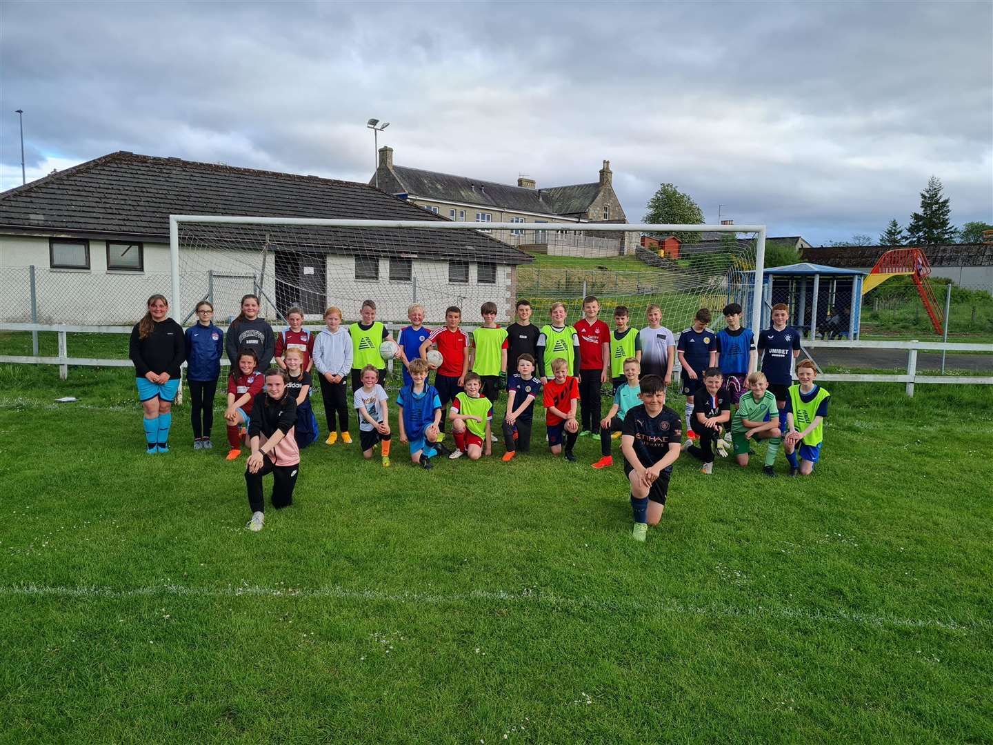 Strathspey Rovers and Strathspey Girls at Cromdale Park. Out front is Aliyah Ligertwood, Strathspey Girls captain and Strathspey Rovers captain, Ralfs Peca.