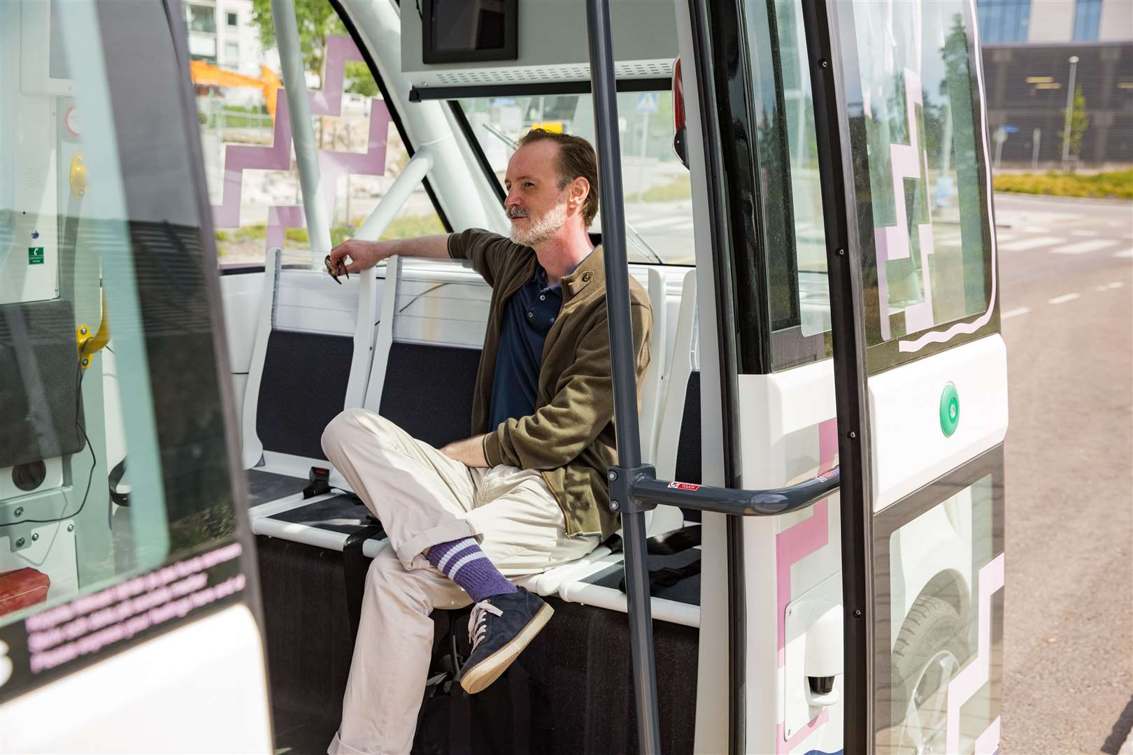 Interior of automated remotely operated bus in Helsinki. Unmanned public transport test on street. Passenger sitting on seat, waiting on bus stop.