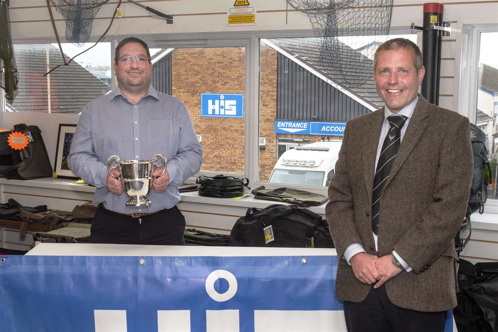 Garry Mackintosh, HIS director, holds the Highland Industrial Supplies Sutherland Cup alongside Steven MacKenzie, Camanachd Association president. Photo: Neil G Paterson