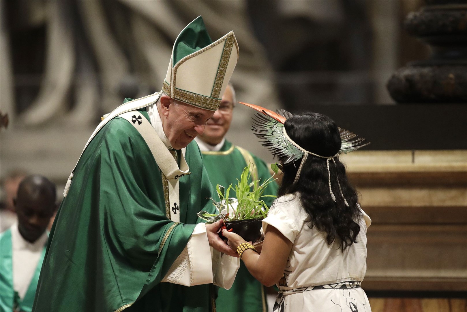 An Amazonian indigenous girl gives Pope Francis a plant during the offertory of a mass in 2019 Alessandra Tarantino/AP)