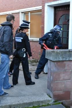 A battering ram is used by police to enter one of the houses raided