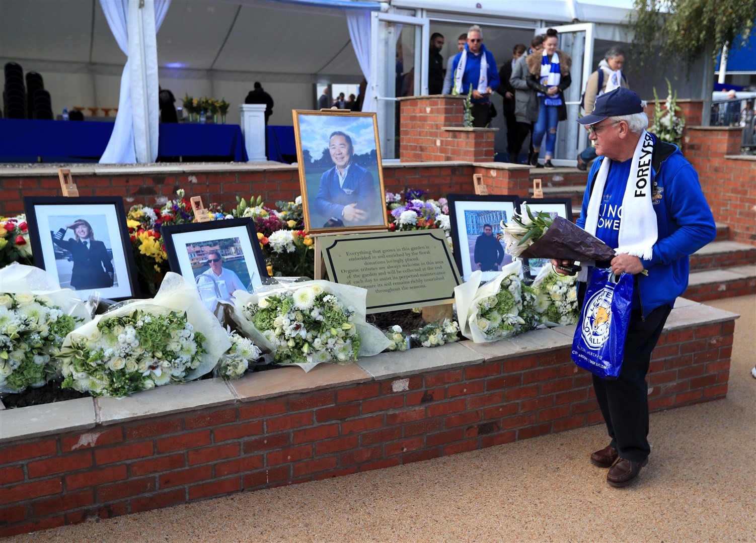 A Leicester City fan places a floral tribute at the Vichai Srivaddhanaprabha Memorial Garden. Mr Srivaddhanaprabha’s home was also targeted in the raid (Mike Egerton/PA)