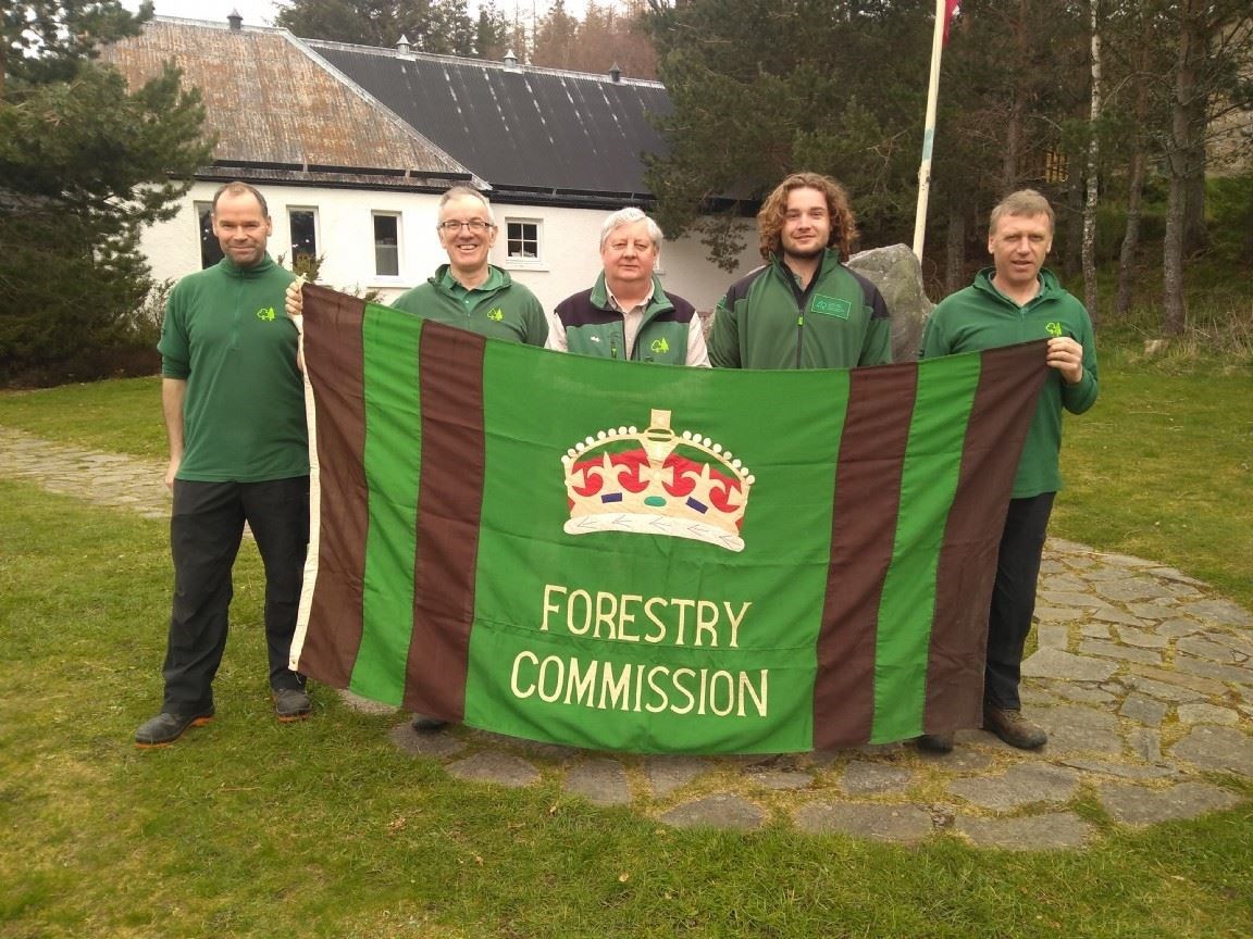 The Glenmore FLS team in 2019. The flag found in an unused storage area and in old Forestry Commission colours could date back to the era of King George. Current FLS Strathspey delivery officer, Brian Duff, is second from left.