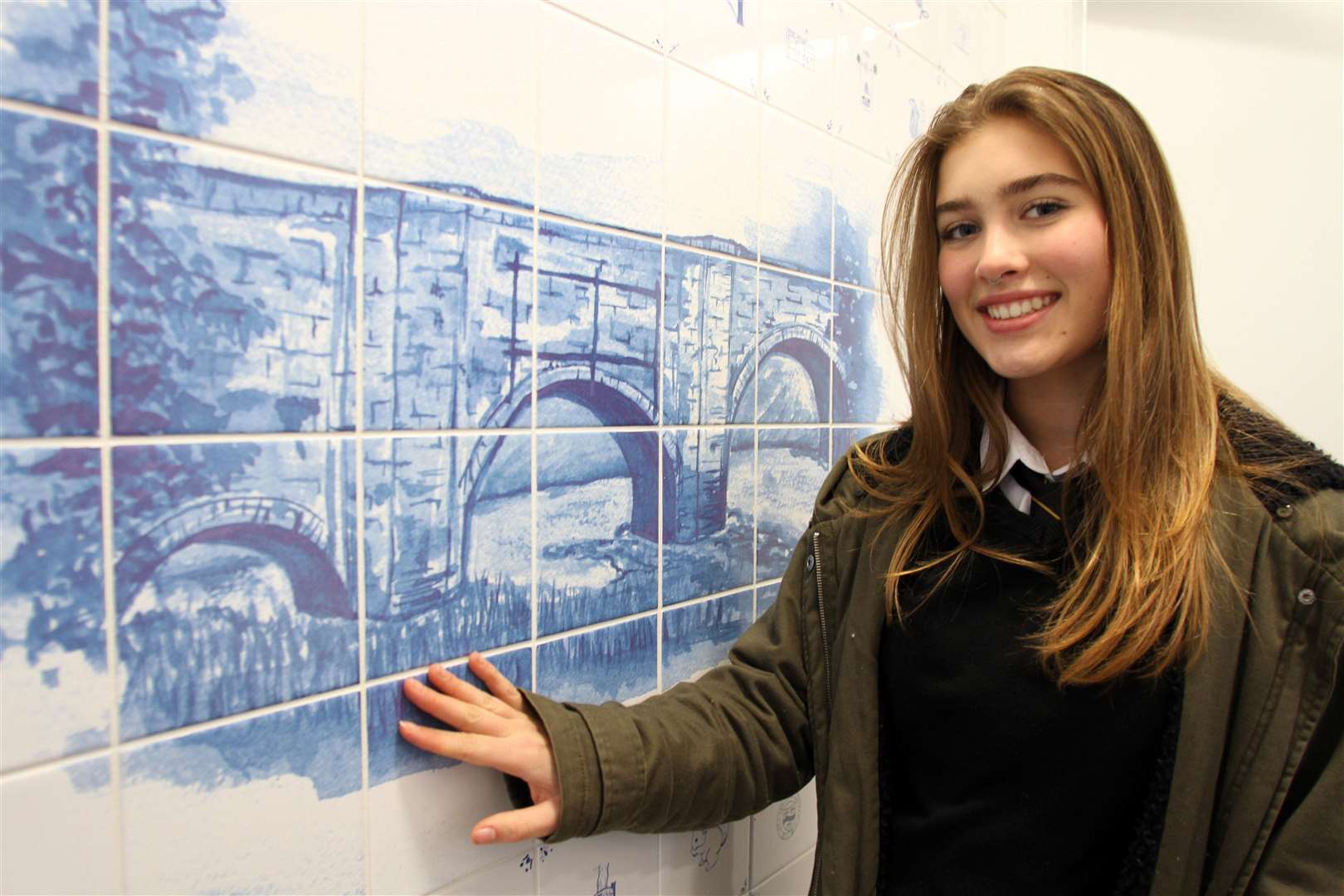 Rosie Trussell with her creation of the local landmark which has been recreated on tiles in the toilet block.