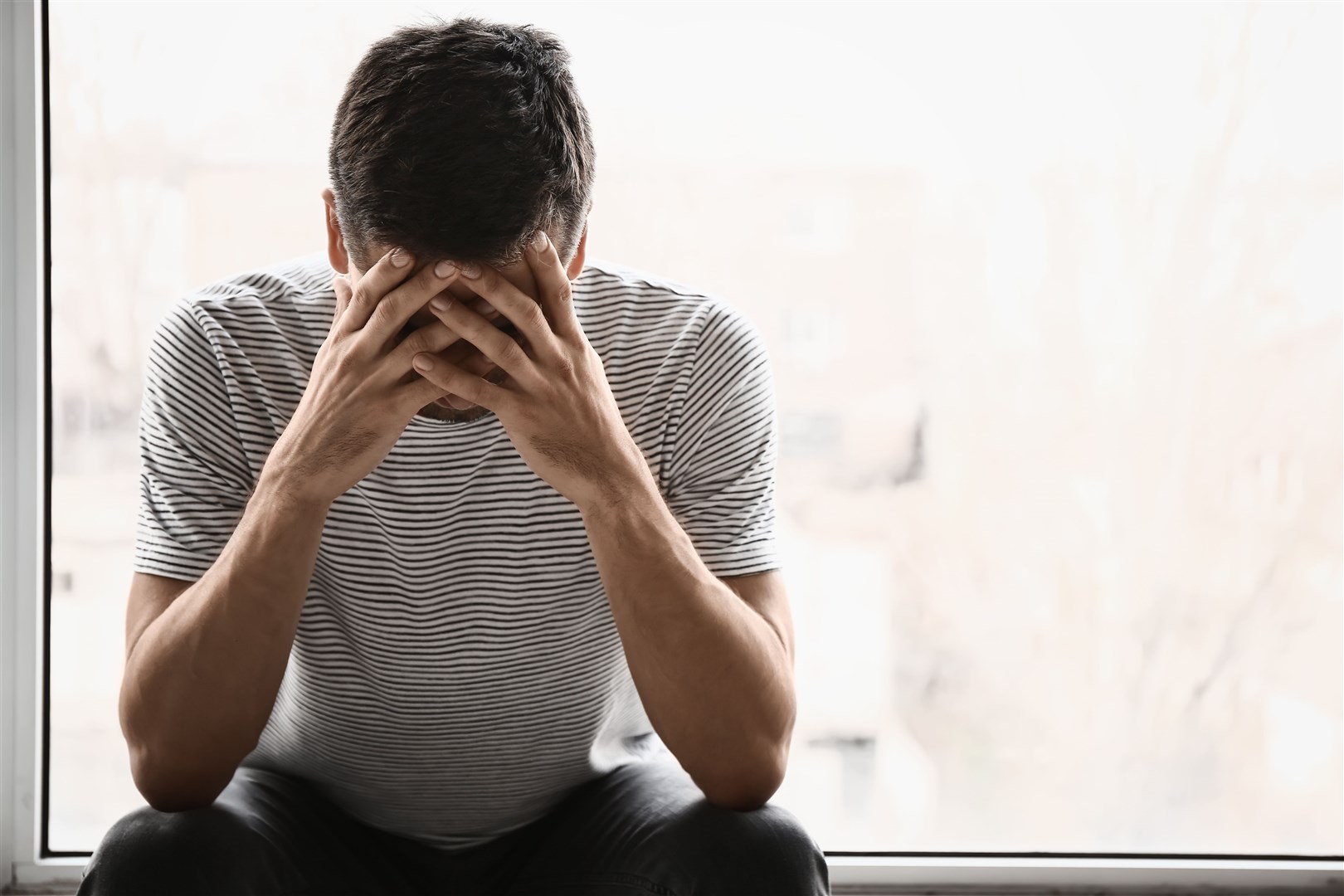 Depressed young man near window.