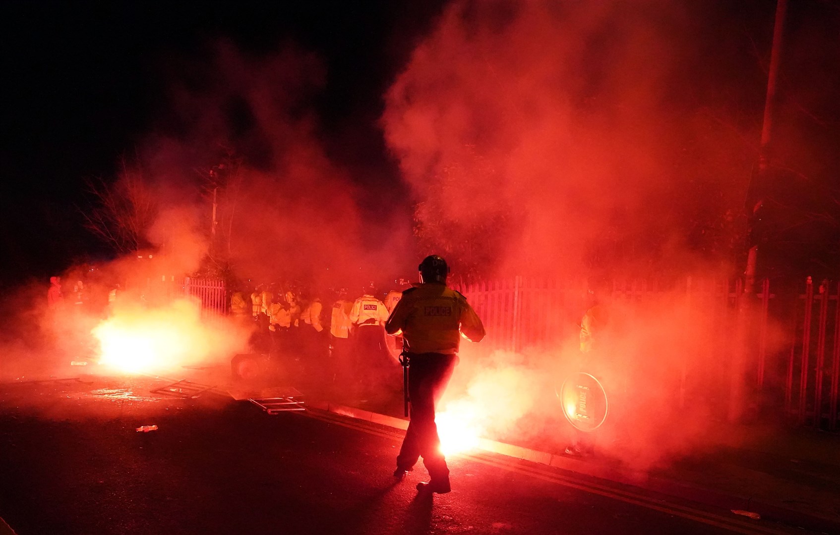 Police attempt to put out flares thrown towards them on Thursday night (David Davies/PA)