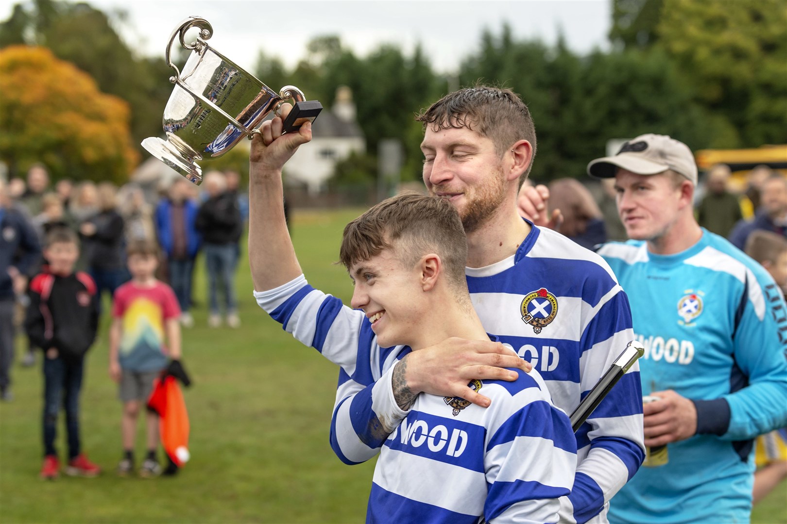 Newtonmore captain Sorley Thomson goes to share the trophy with his team.