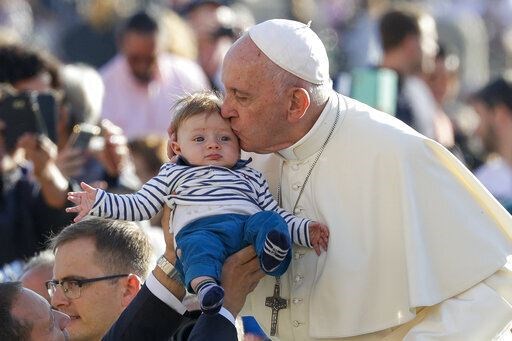 Francis kisses a baby passed to him in St Peter’s Square (Andrew Medichini/AP)