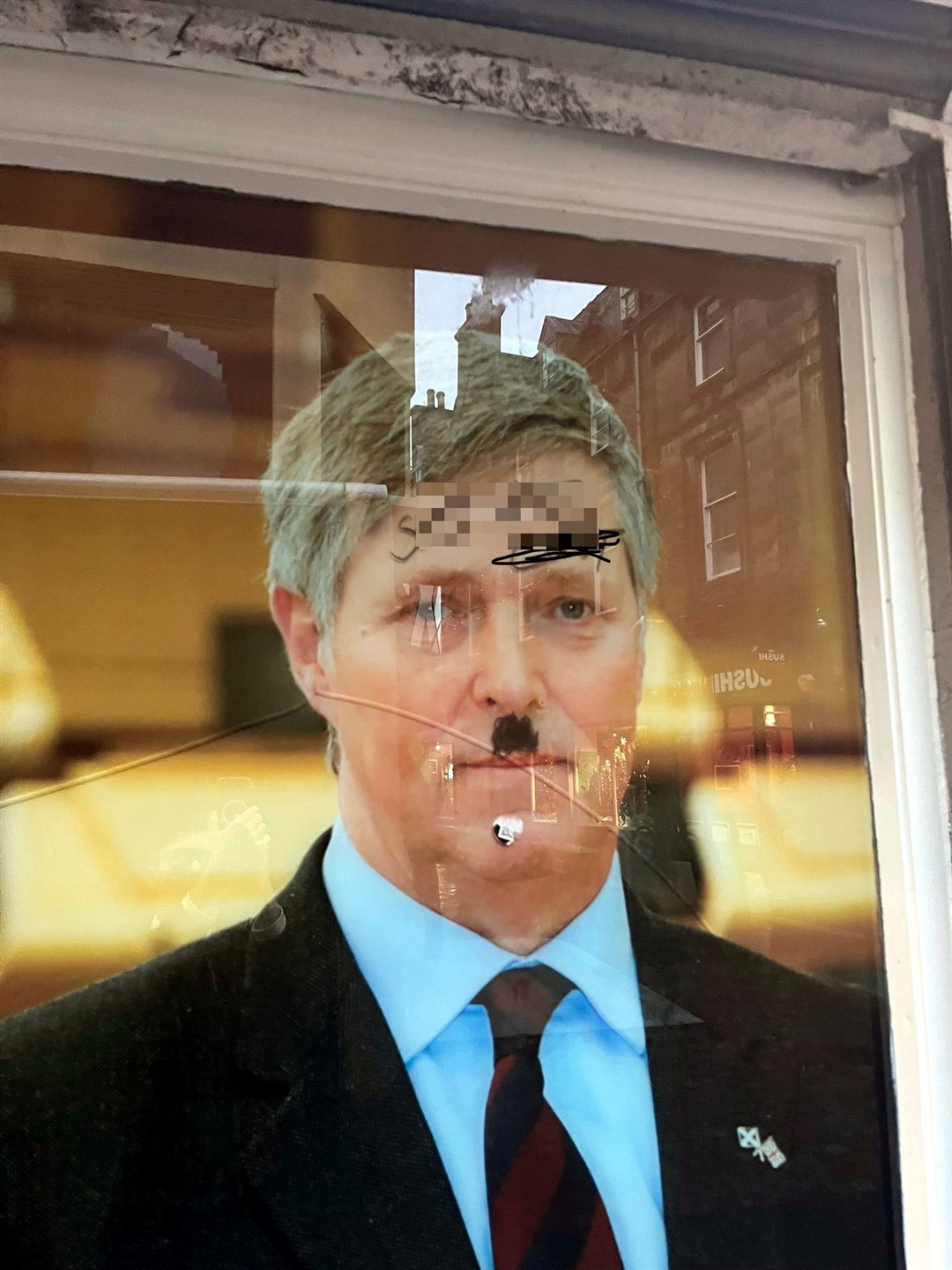 The defaced image of MSP Edward Mountain in his constituency office window