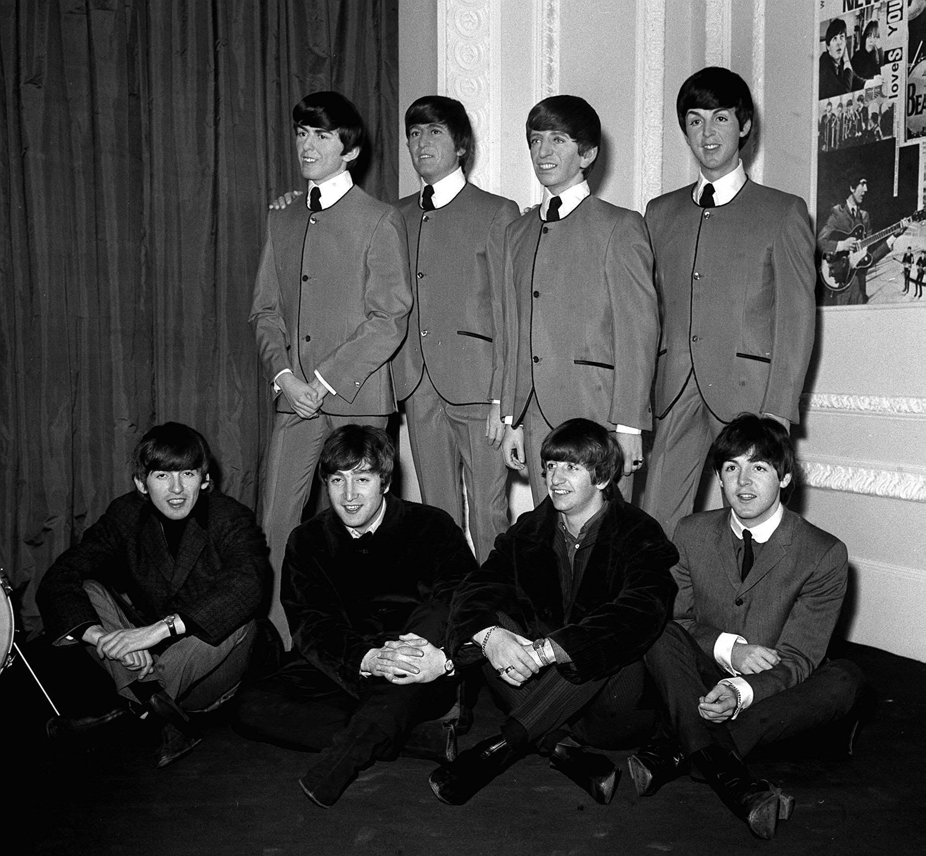 The Beatles seated in front of their waxwork models wearing Pierre Cardin-designed suits, at Madame Tussauds in London (PA)