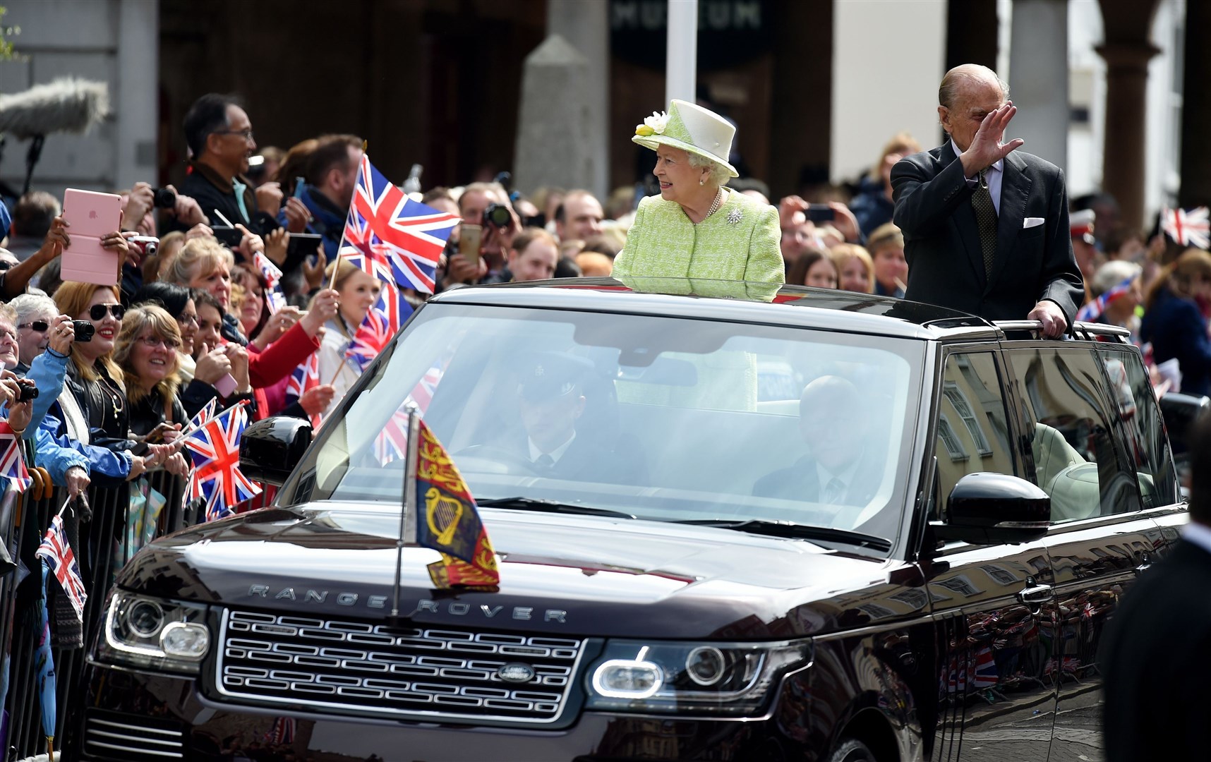 The Queen waves to well wishers from a open top Range Rover for her 90th birthday celebrations (Andrew Matthews/PA)