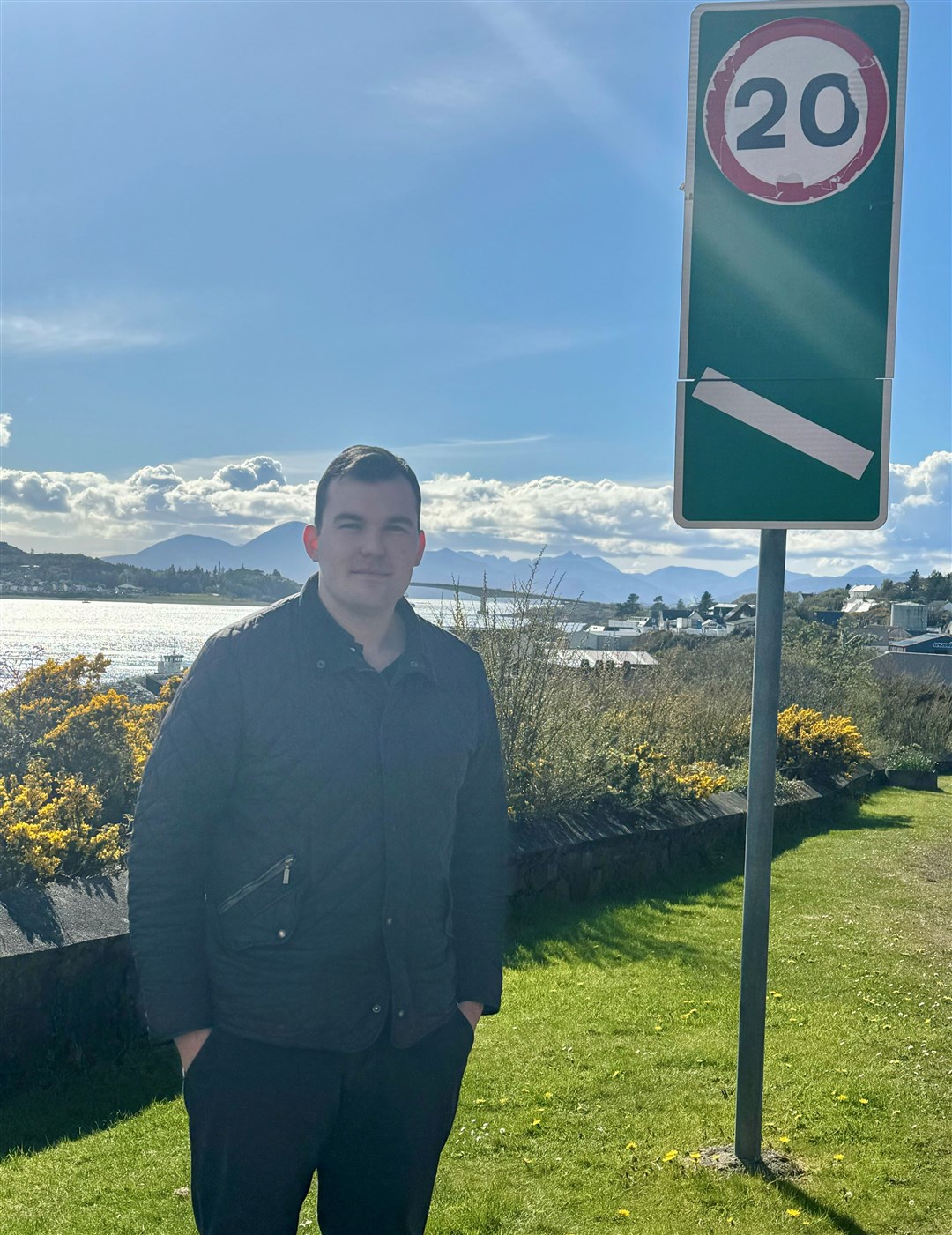 Cllr Ruraidh Stewart next to one of the 20mph limit signs entering Kyle of Lochalsh.