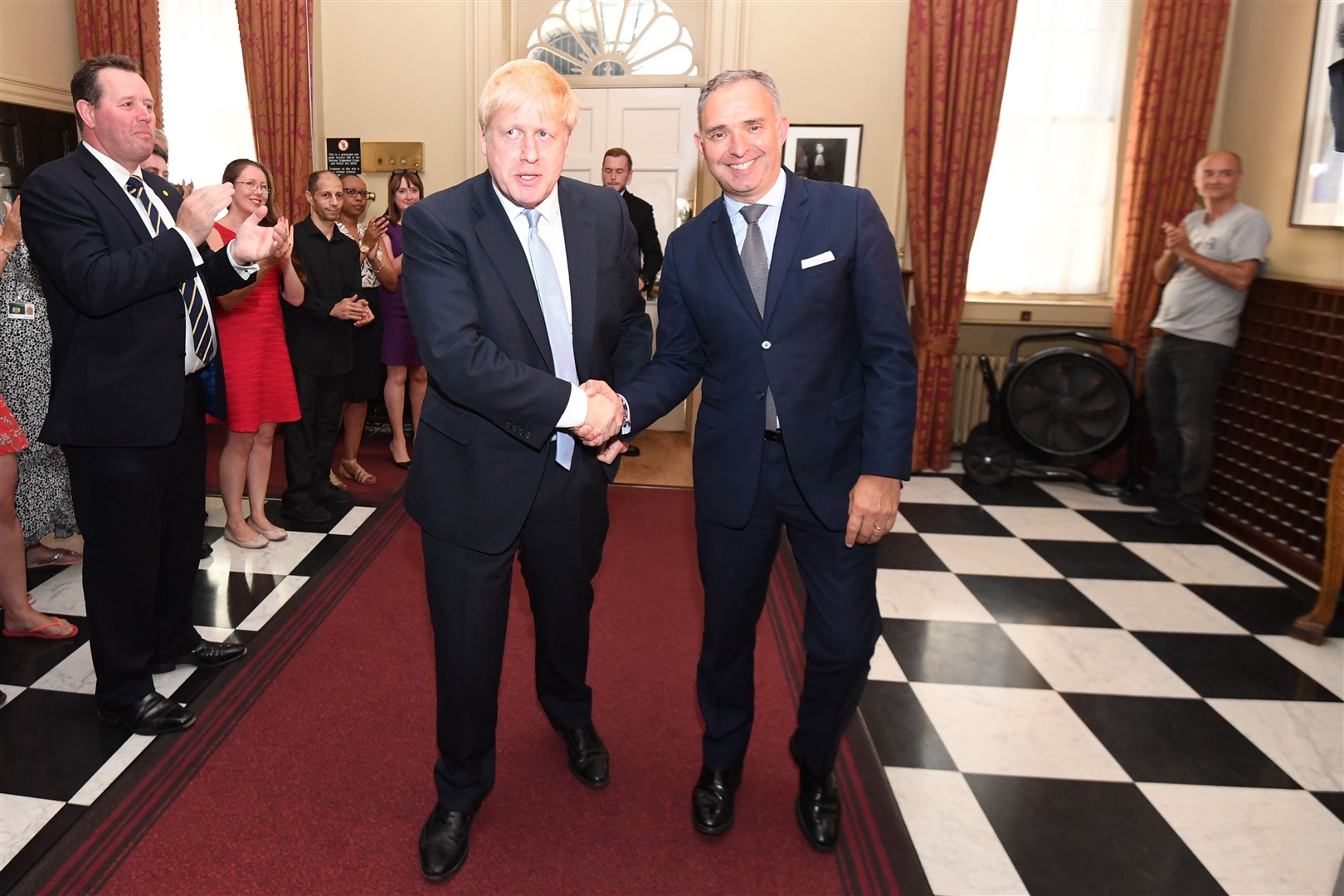 Prime Minister Boris Johnson shaking hands with Sir Mark Sedwill, as he is clapped into 10 Downing Street by Mark Spencer (left) and Mr Cummings (right) (Stefan Rousseau/PA)