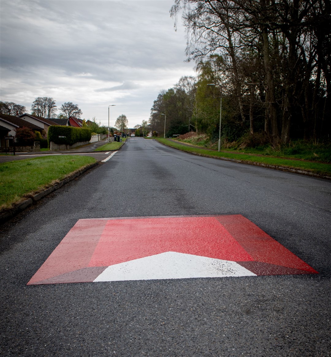 The design of the fake speed bumps aims to give the illusion of depth and a 3D obstacle in the road.