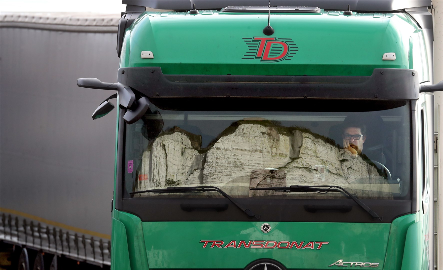 The White Cliffs are reflected in the windscreen of a lorry whilst the driver sits his cab and queues (Gareth Fuller/PA)