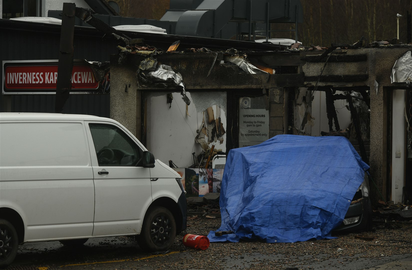 The car covered by tarpaulin was today still at the burnt-out building at Fairways Business Park in Inverness. Picture: James Mackenzie