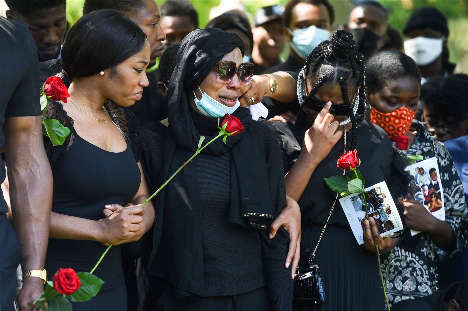 Khafi Kareem (left) and Victoria Oloniluyi (centre), the sister and mother of Alexander Kareem, prepare to lay roses on his coffin (Kirsty O’Connor/PA)