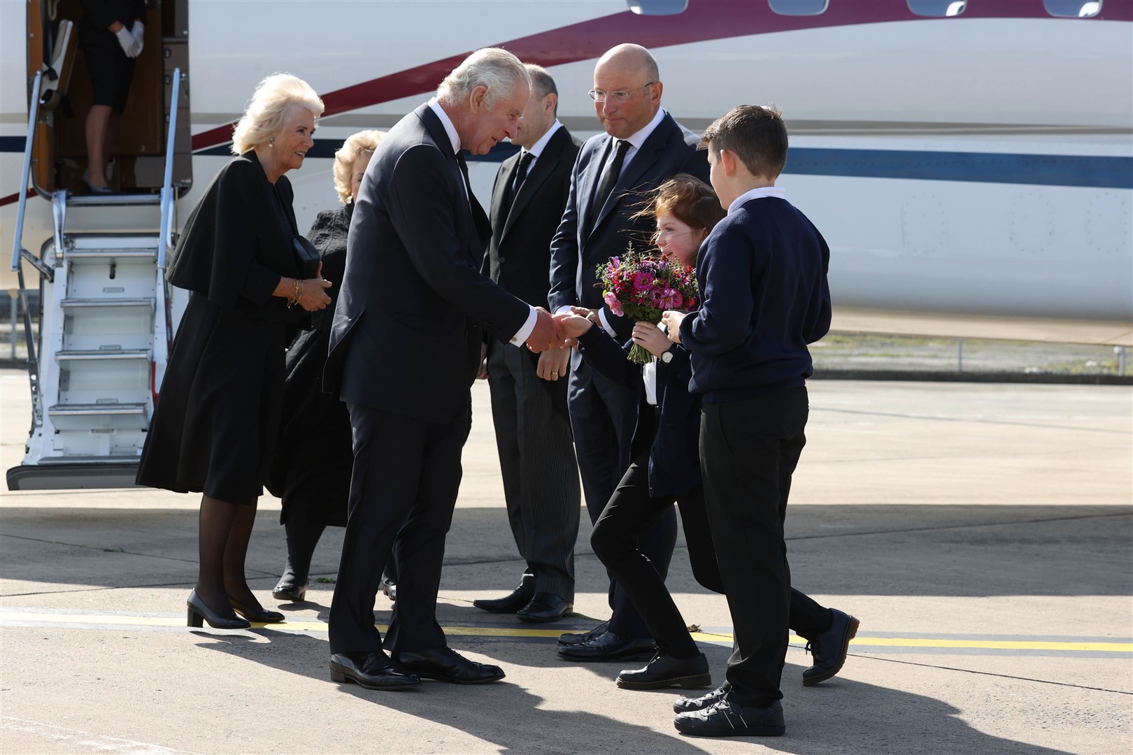 The Queen Consort and King Charles III are greeted at Belfast City Airport (Liam McBurney/PA)