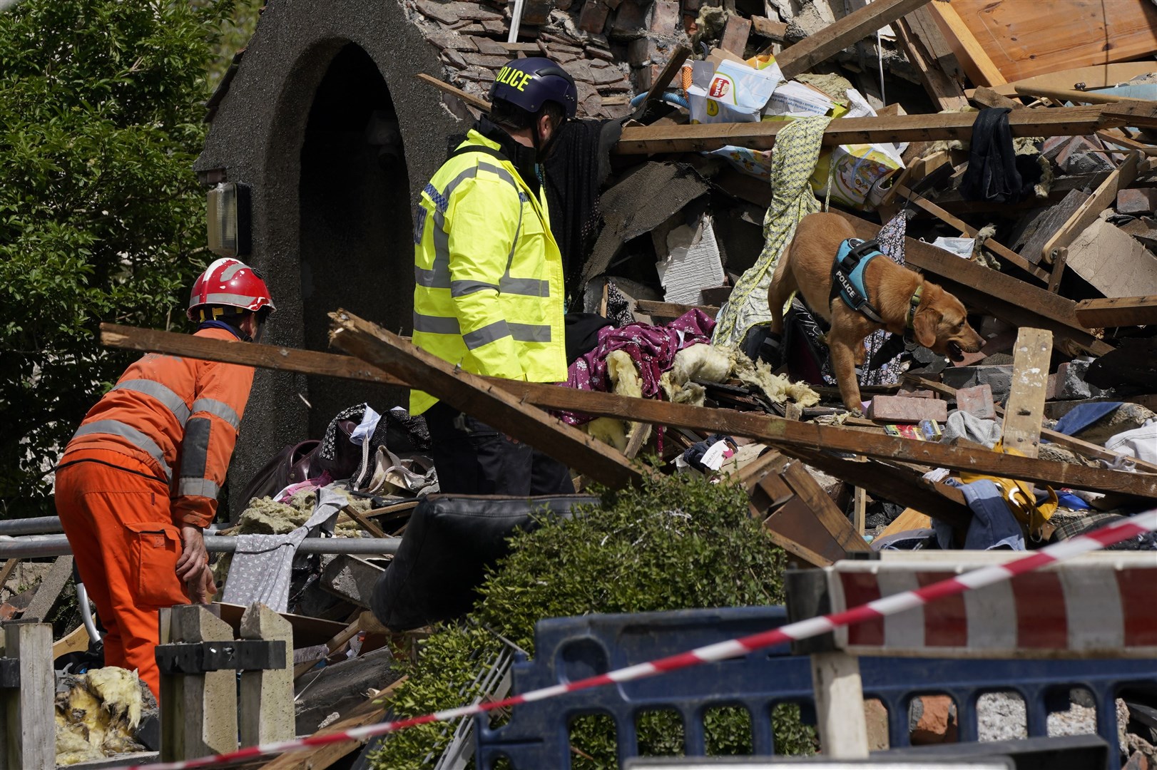 Emergency workers use a sniffer dog to search through rubble (Danny Lawson/PA)